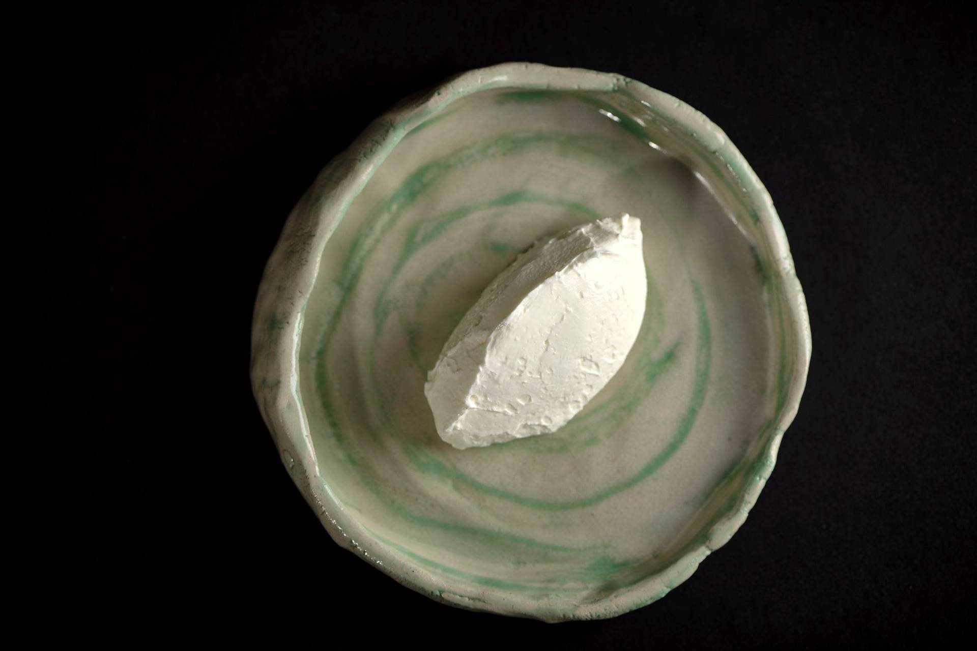 a spoon of creme fraiche on a ceramic plate with black background