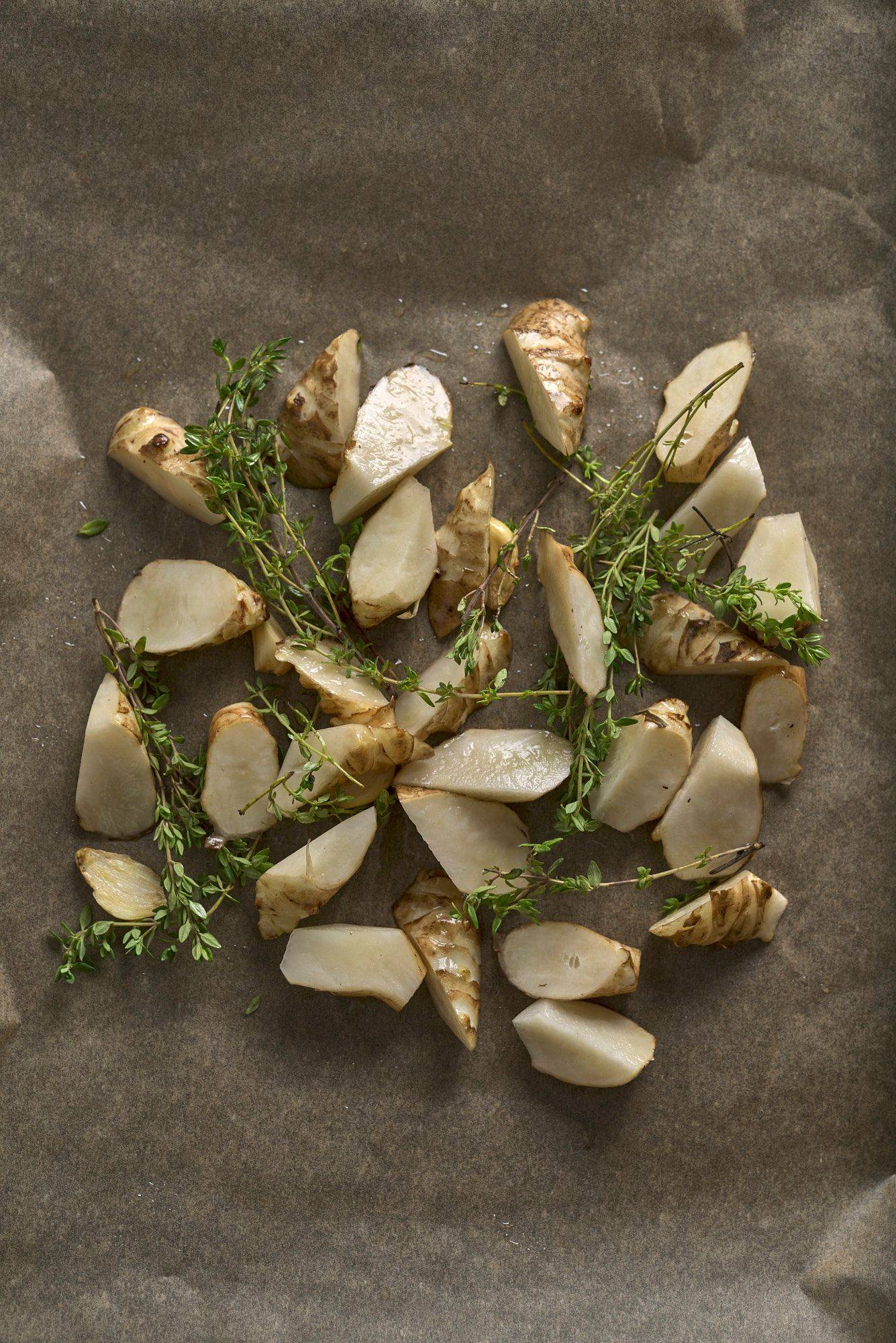 raw marinated jerusalem artichokes on a baking sheet