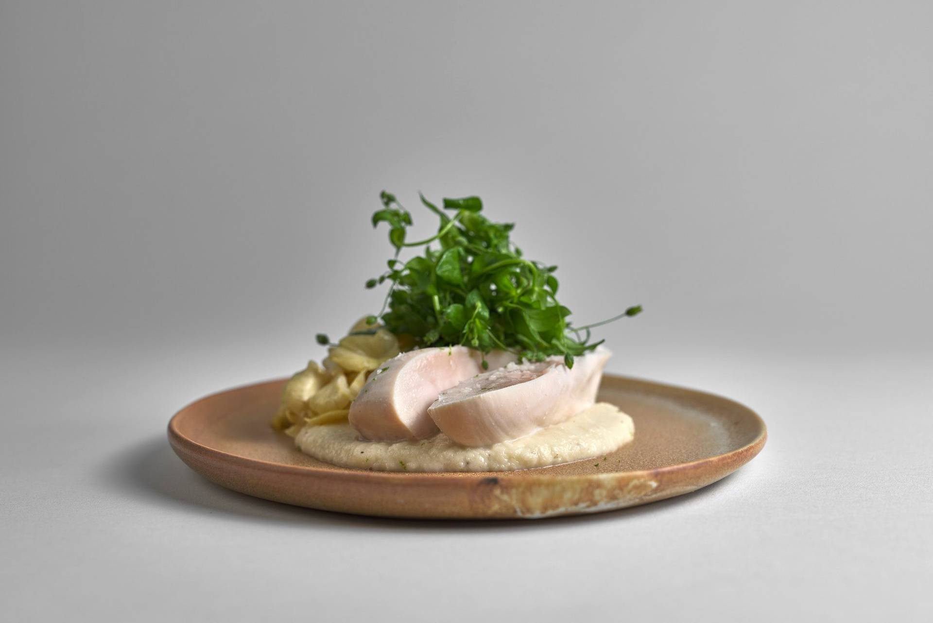 Coconut Poached Chicken with black salsify, chickweed & lemon mushrooms on white background