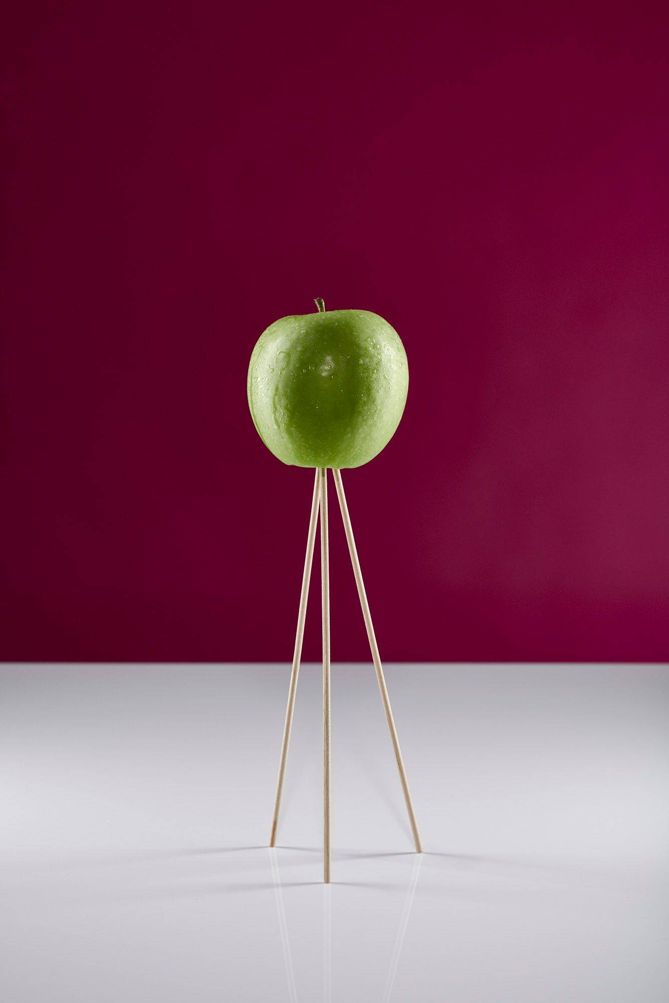 green apple on wooden skewers with white and pink background