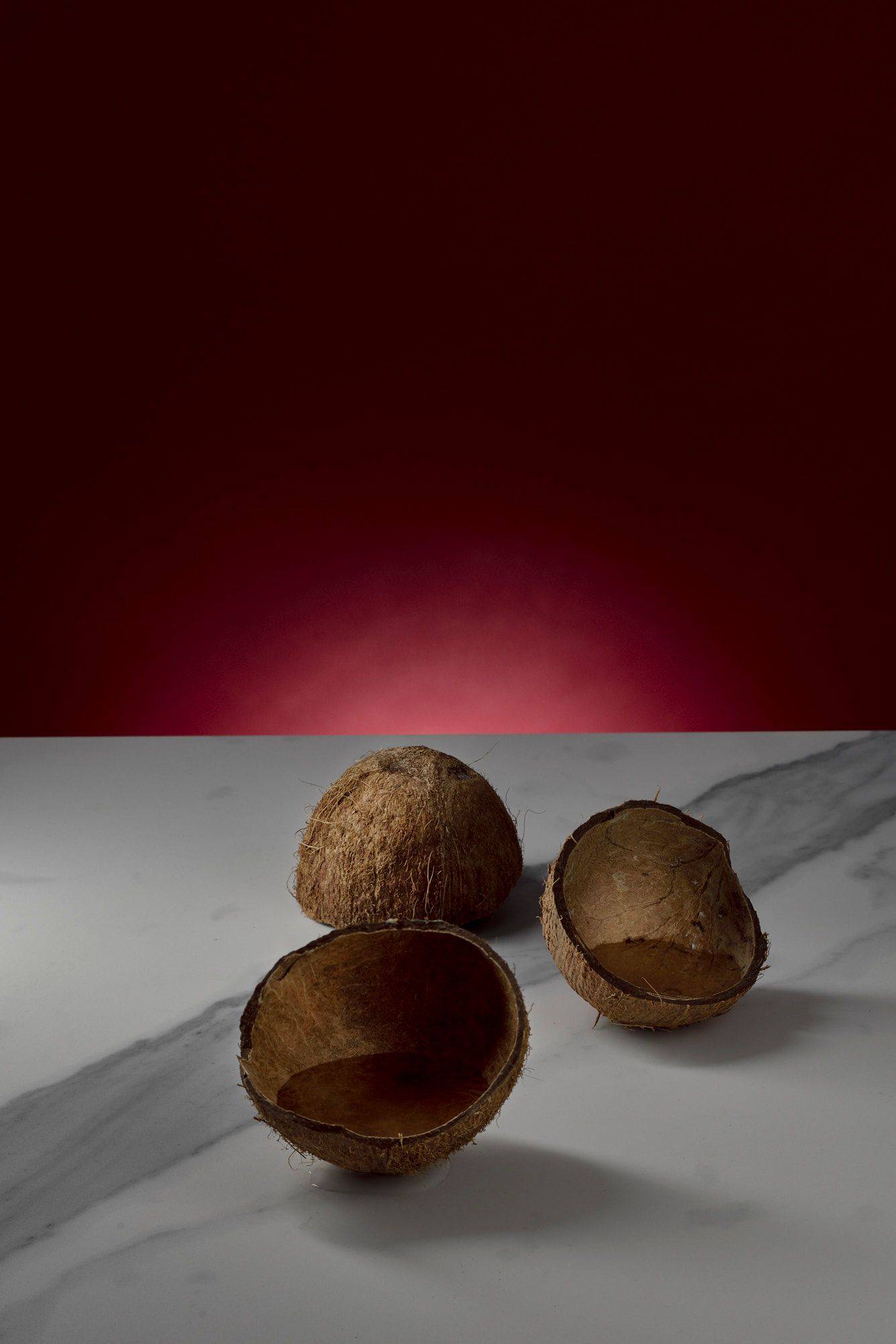 coconut water in coconut shells on marbled sapienstone top with red background