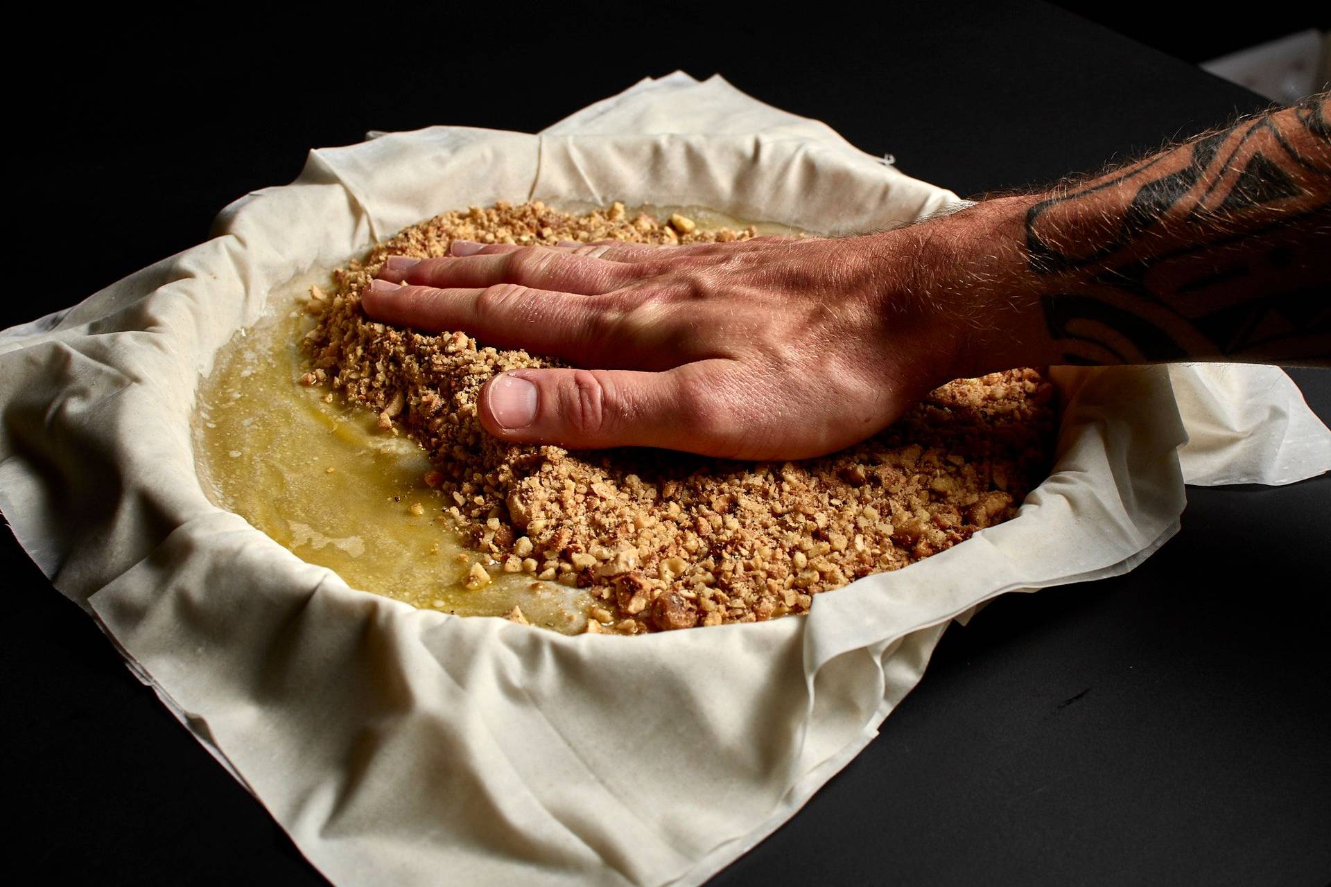 making baklava with hazelnuts and walnuts in a baking pan with black background