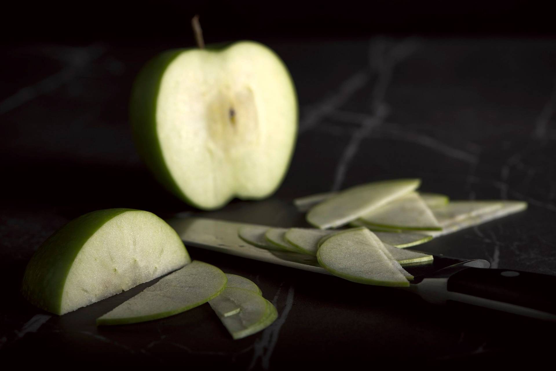 a green cut apple on a gray sapienstone top