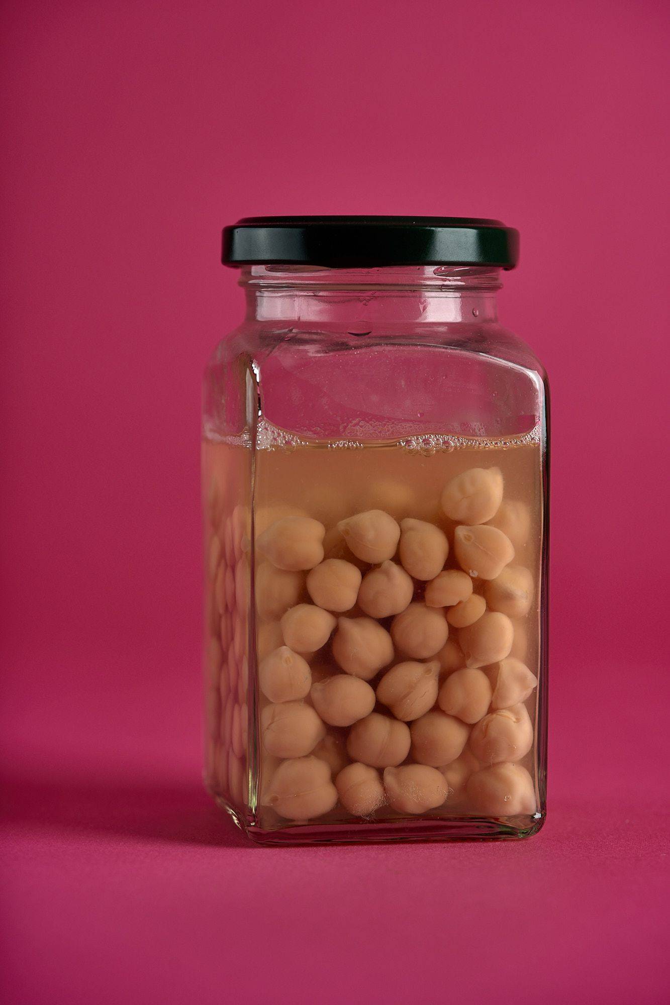 a jar with chickpeas on pink background