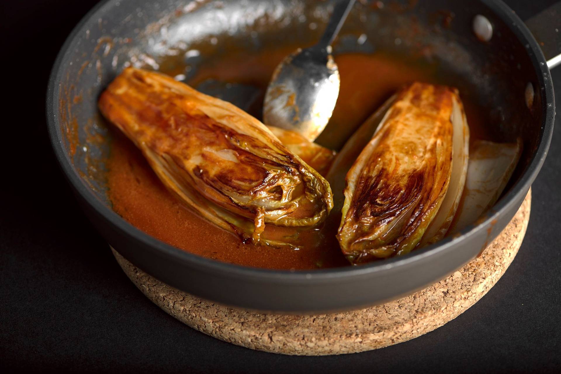 rosehip braised chicory in a small pan with black background