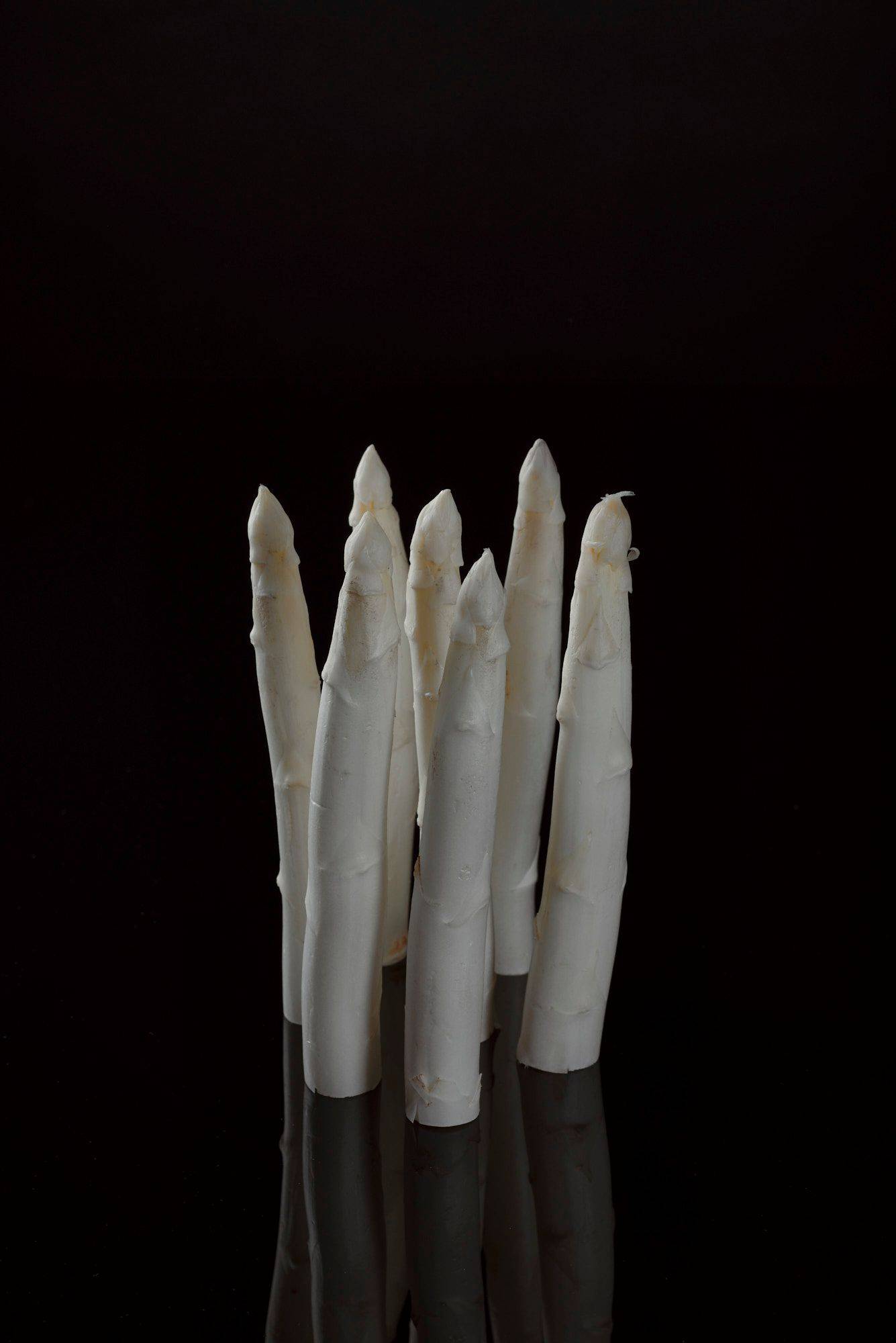 seven pieces of white asparagus with black background