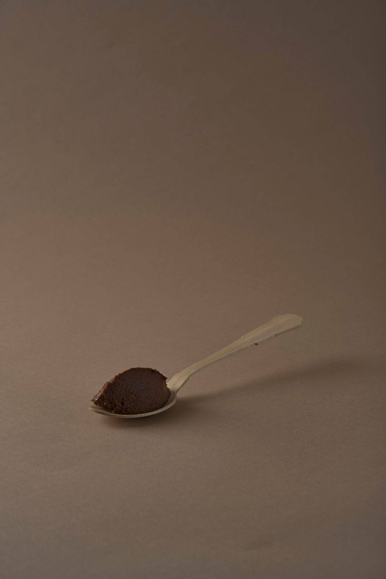 miso paste on a wooden spoon with brown background