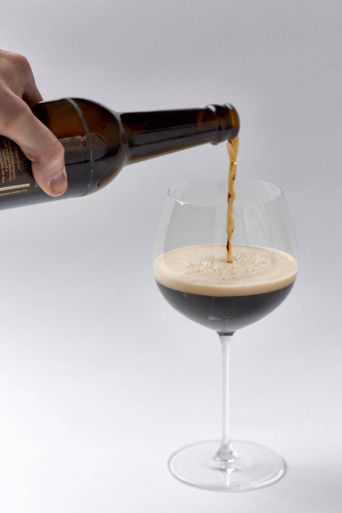 pouring a glass of dark beer with white background