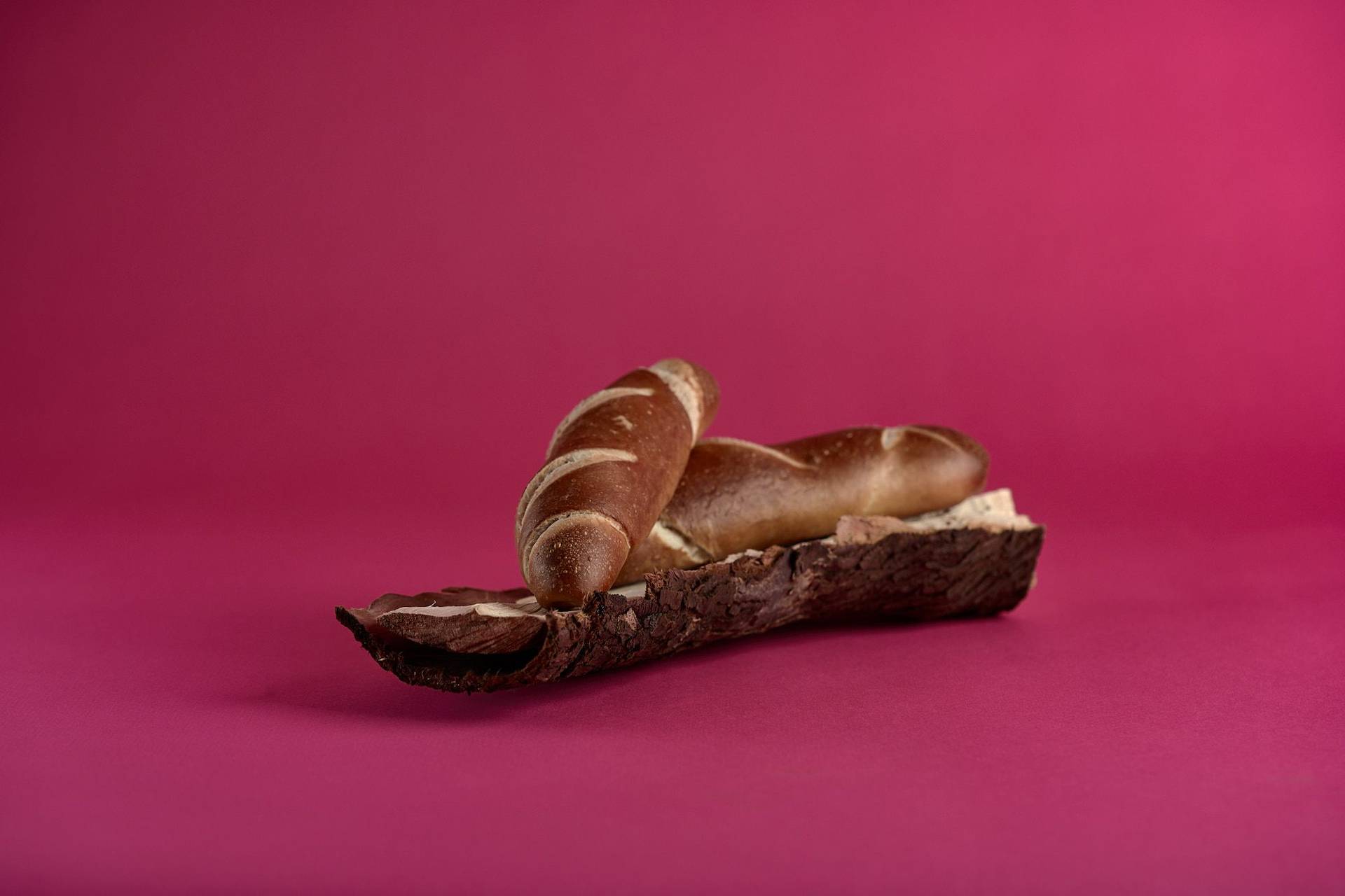 pretzel sticks on a piece of wood on pink background