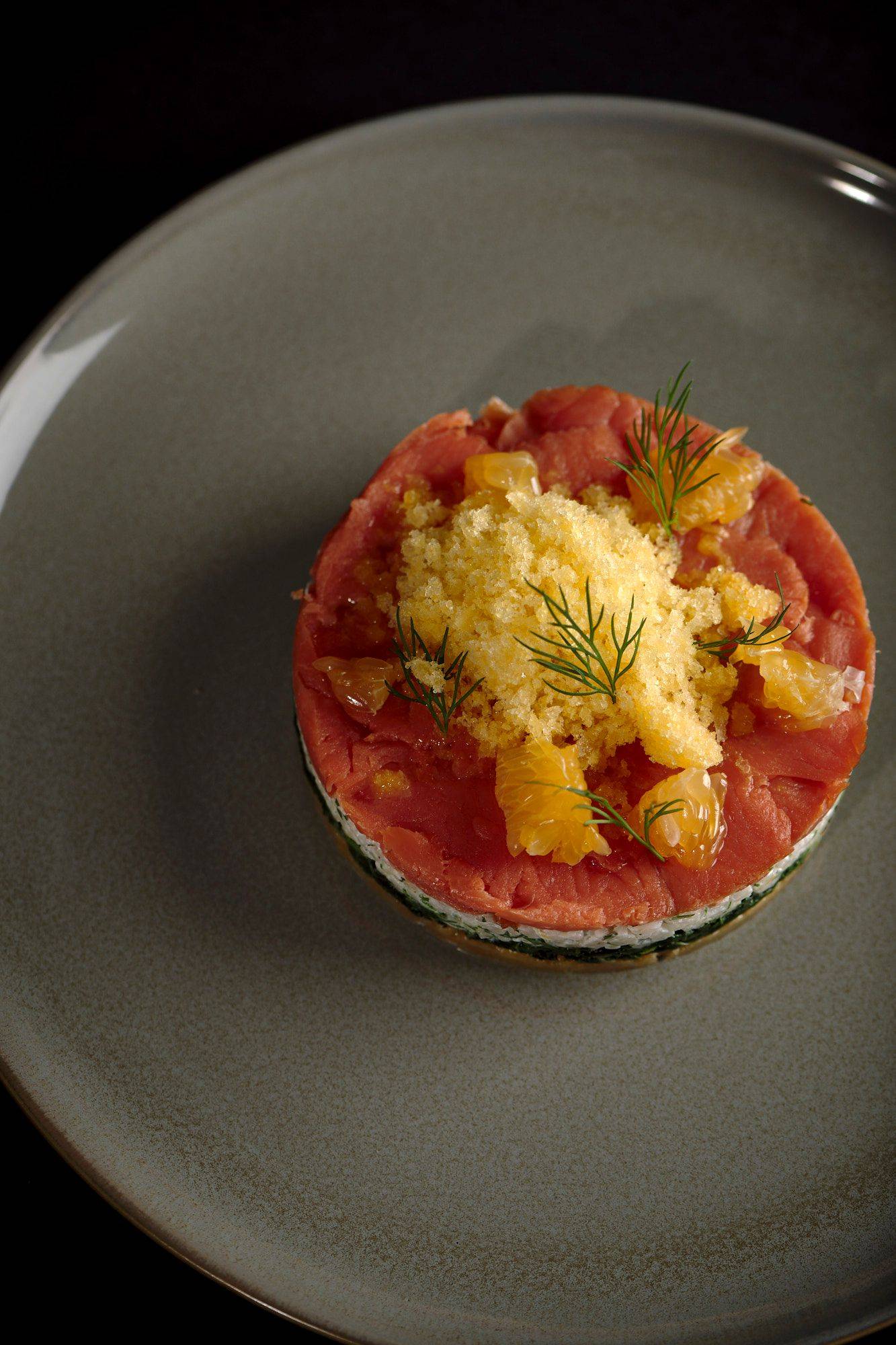 cured salmon tart with tangerine granita on a gray plate with black background