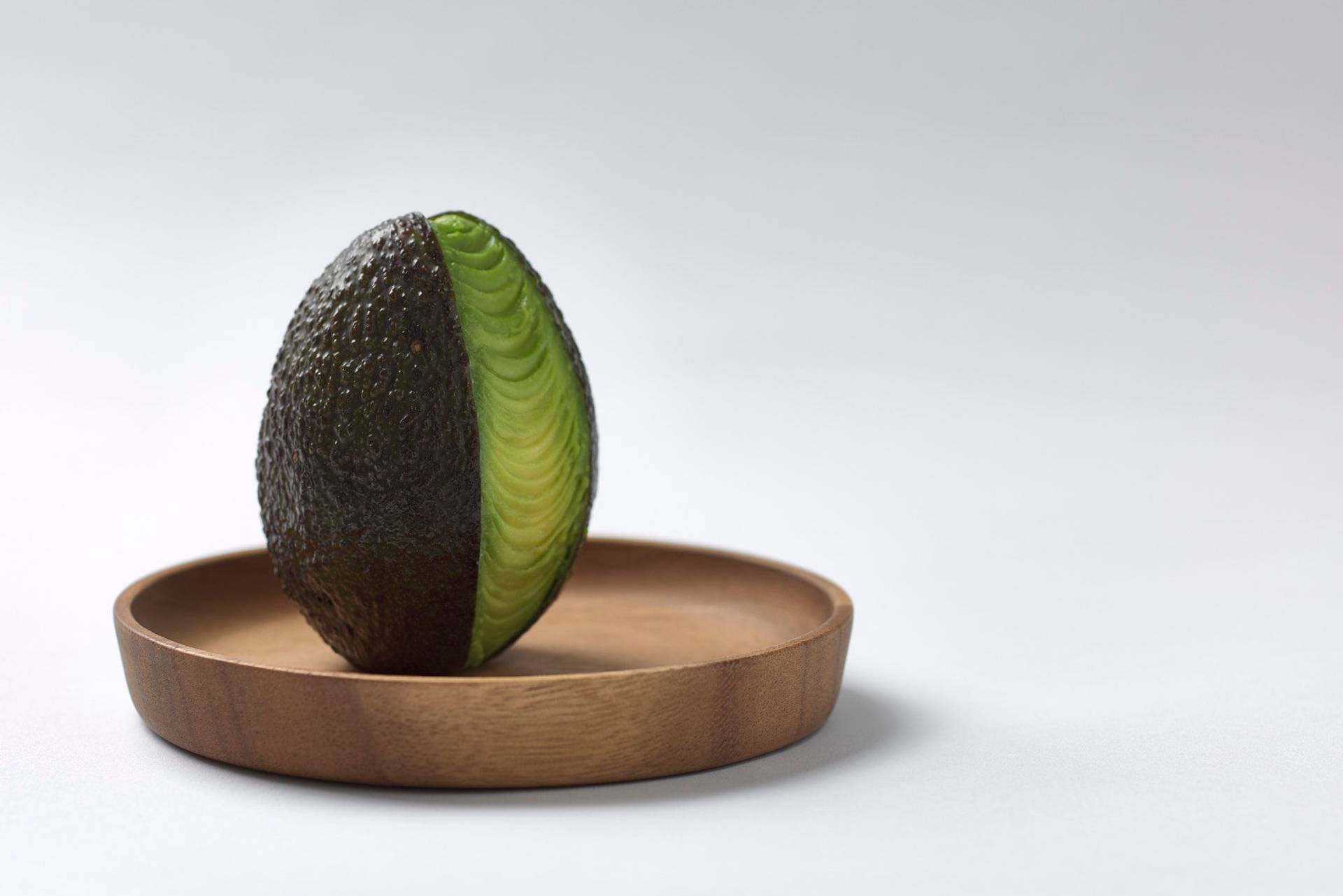 eine avocado auf einem holzteller mit weißem hintergrund