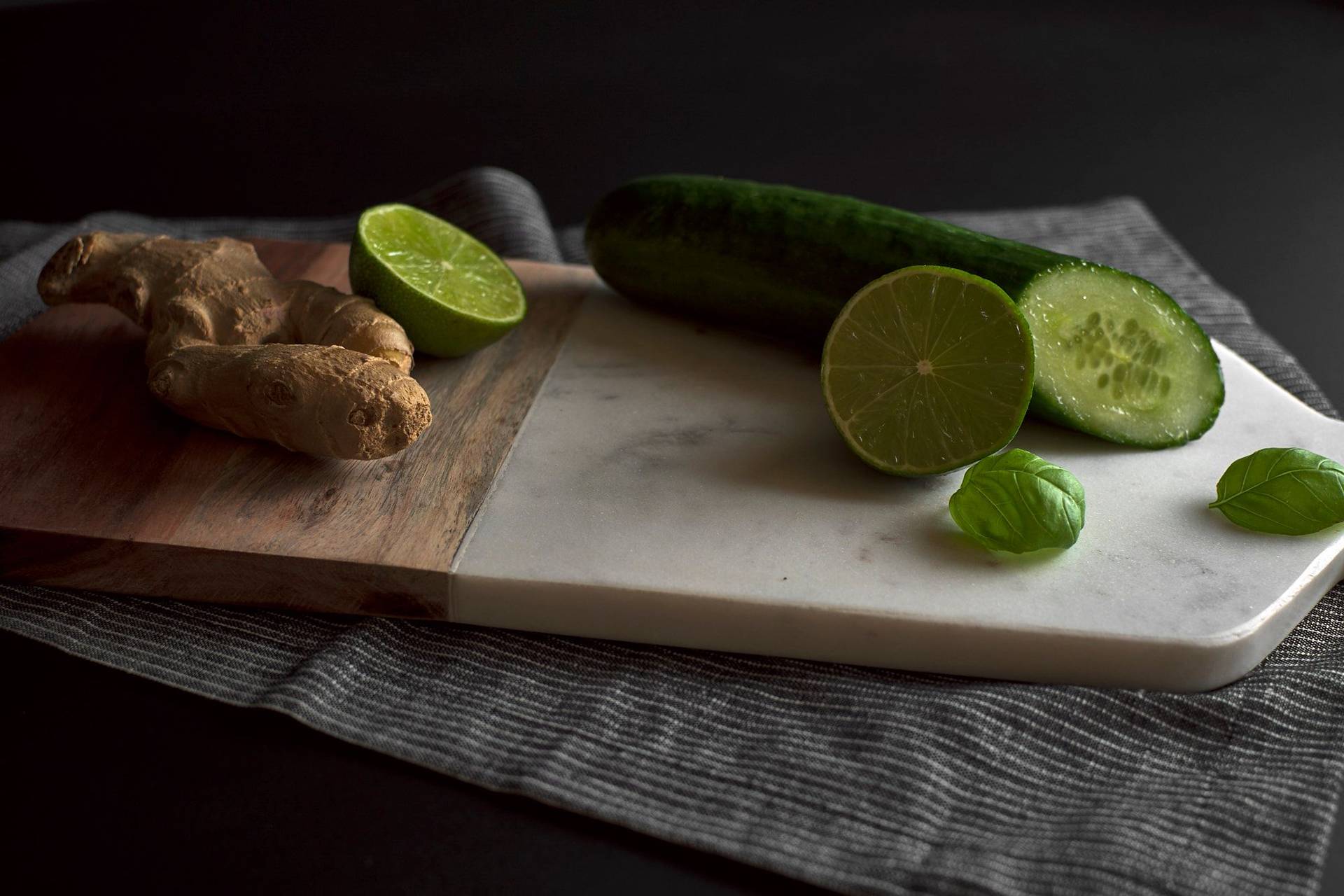cucumber, ginger and basil on a marble cutting board with black background 