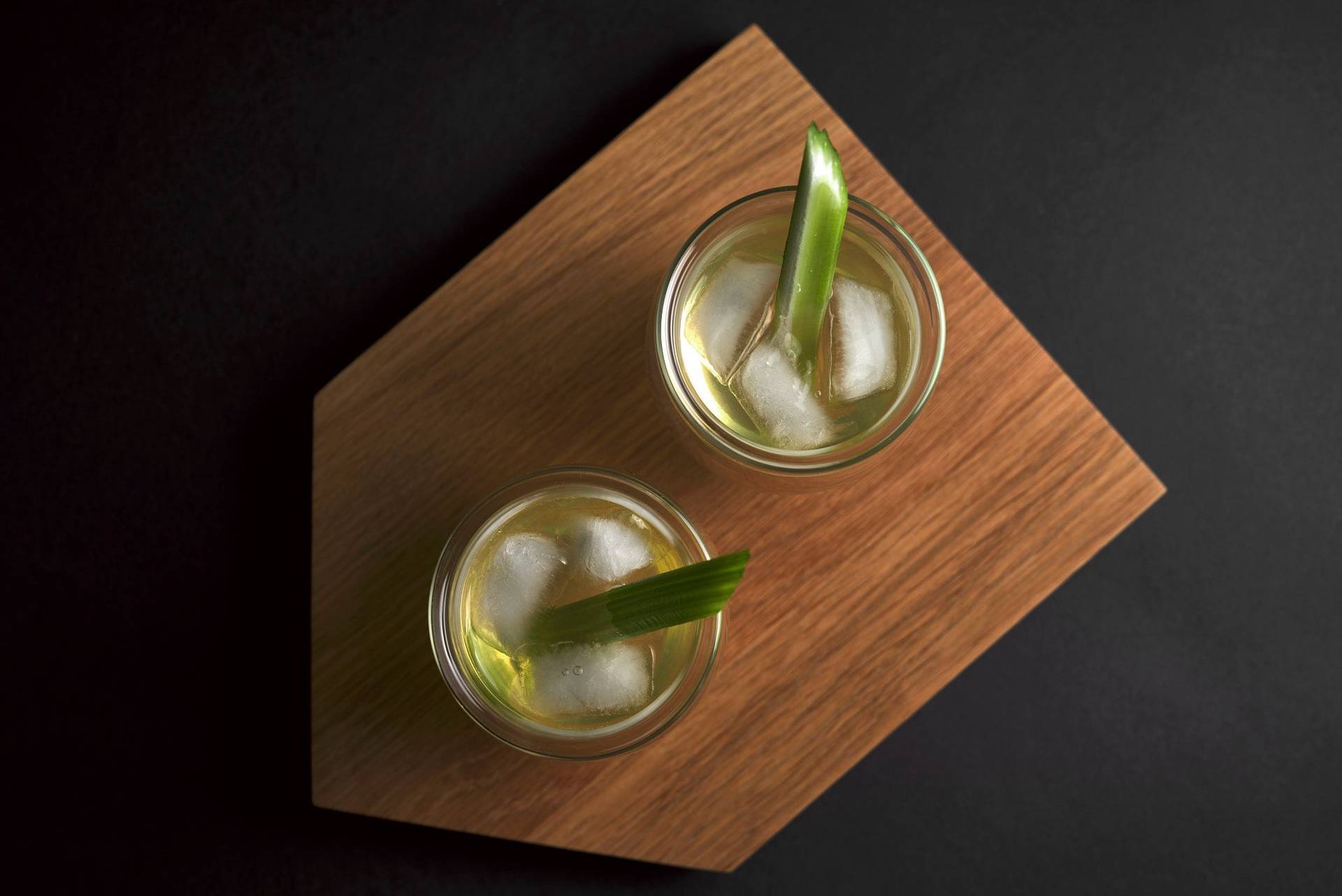 two glasses of white bloody mary on a wooden tray with black background