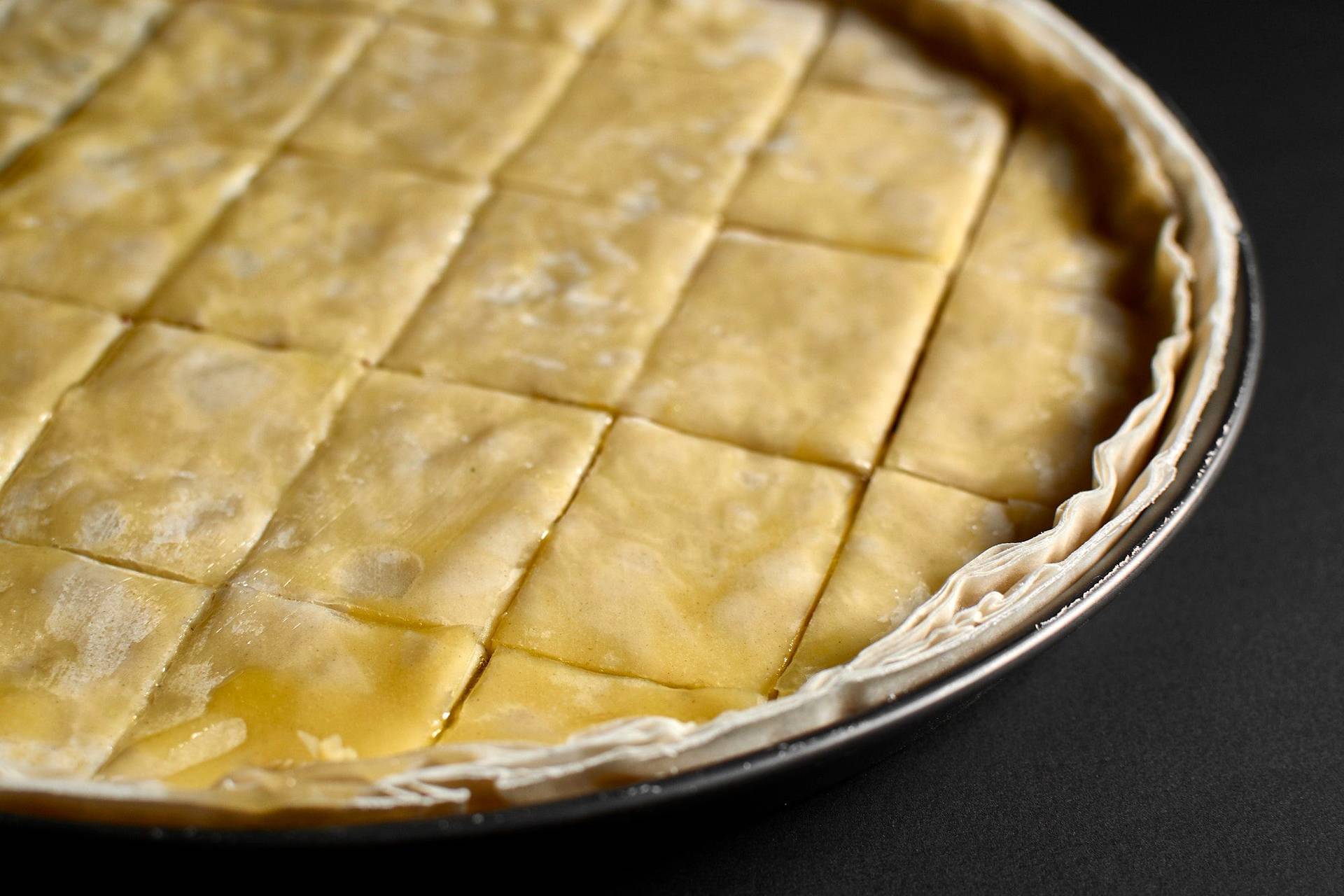 making baklava with hazelnuts and walnuts in a baking pan with black background