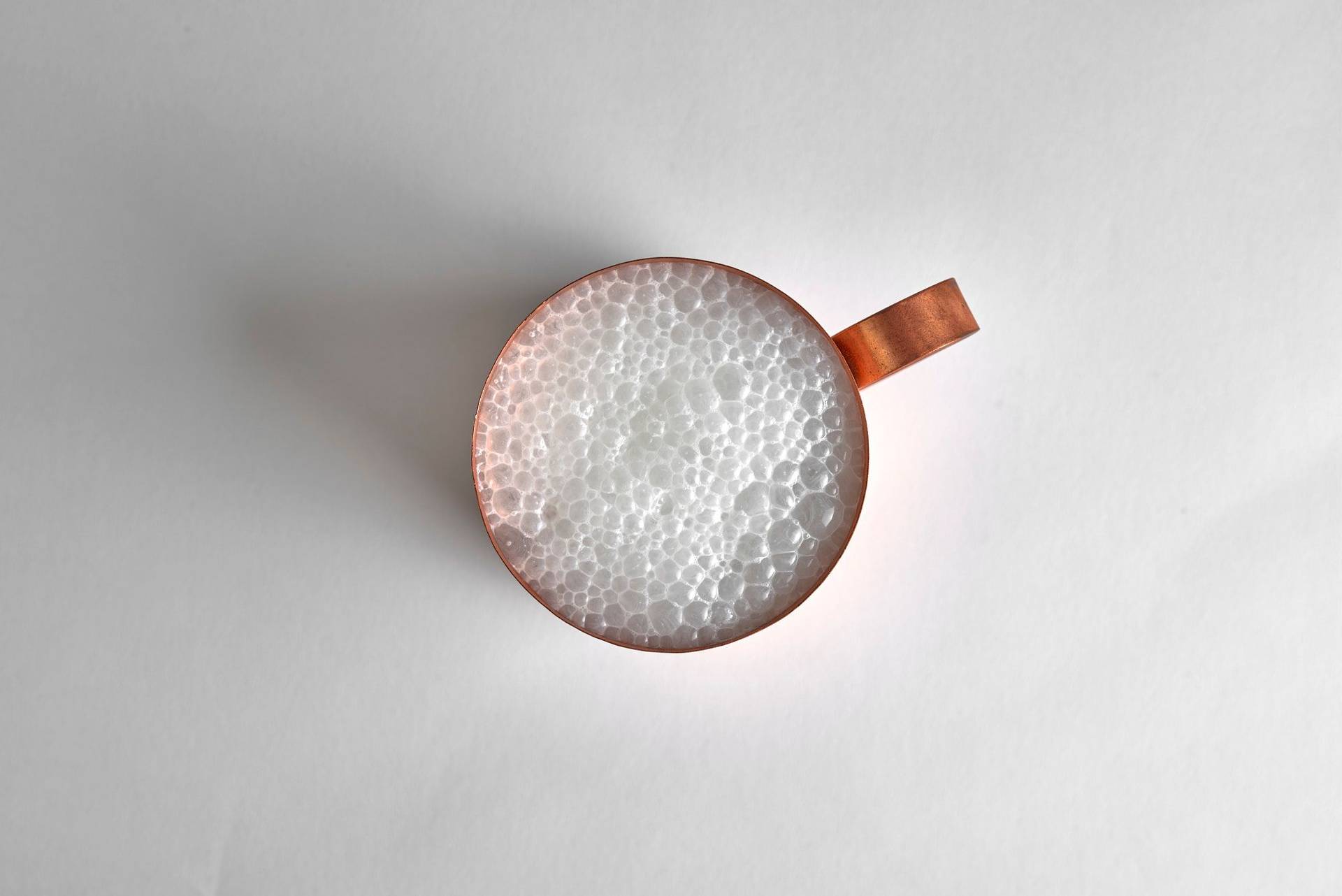foamy ayran in a copper cup with white background