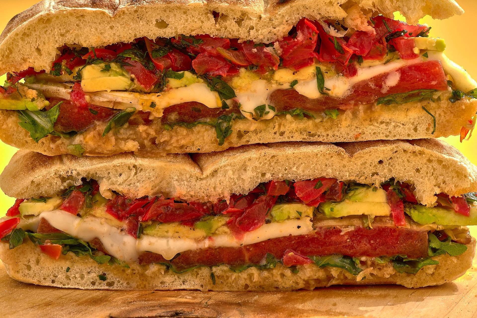 vegetarisches sandwich mit gegrillter wassermelone gremolata knoblauchpaste und käse auf holzbrett mit gelbem hintergrund