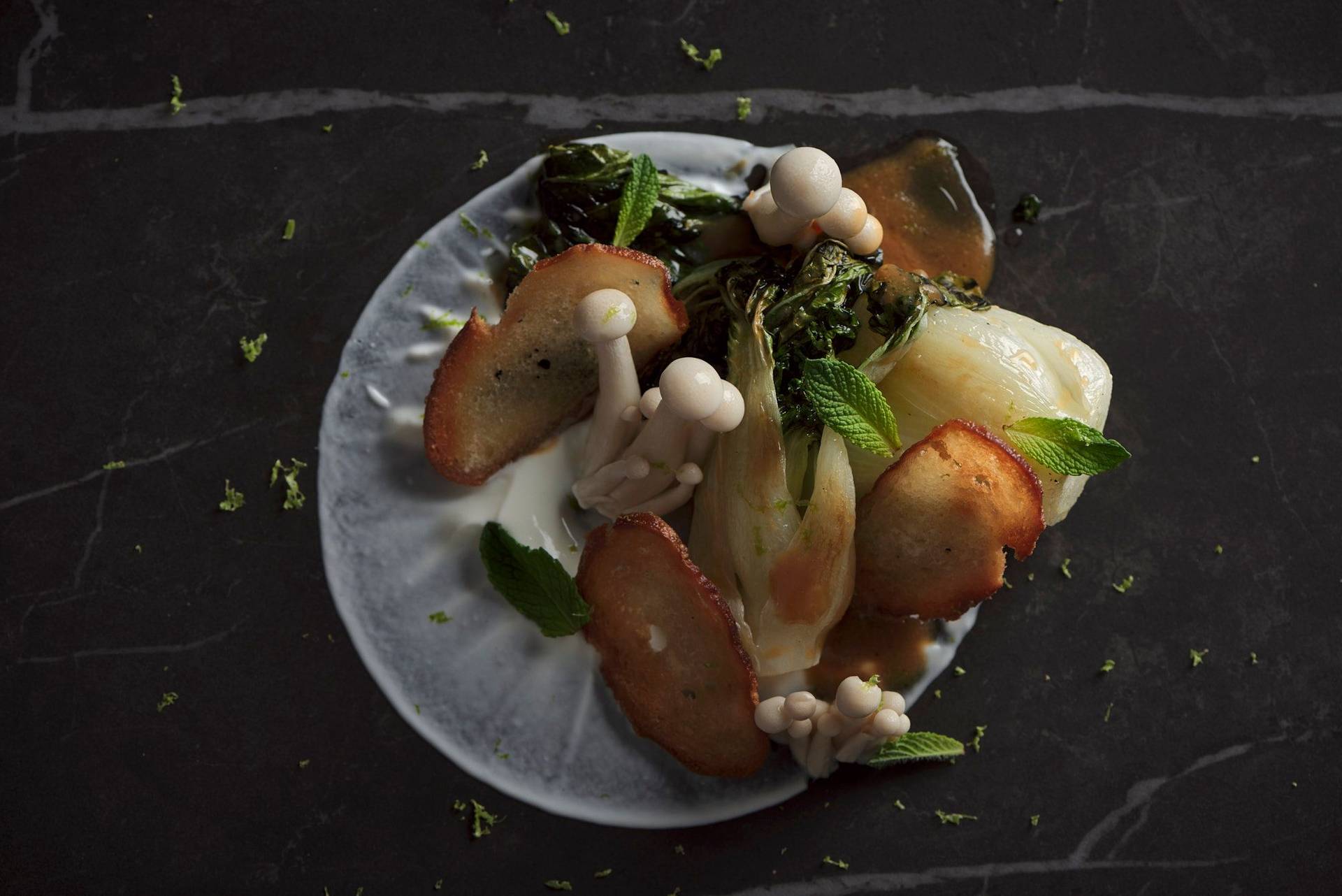 miso roasted pak choi with mushroom pickles and pretzel crisps on a gray sapienstone top