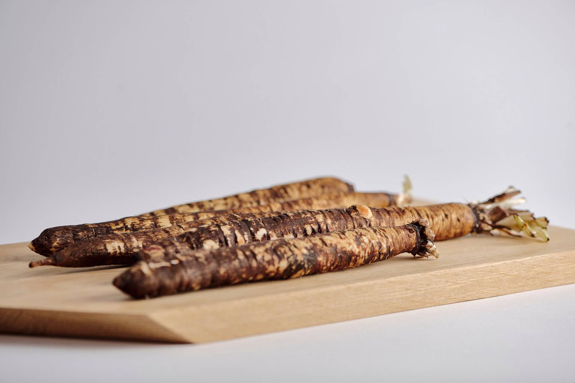 black salsify on a wooden board with white background