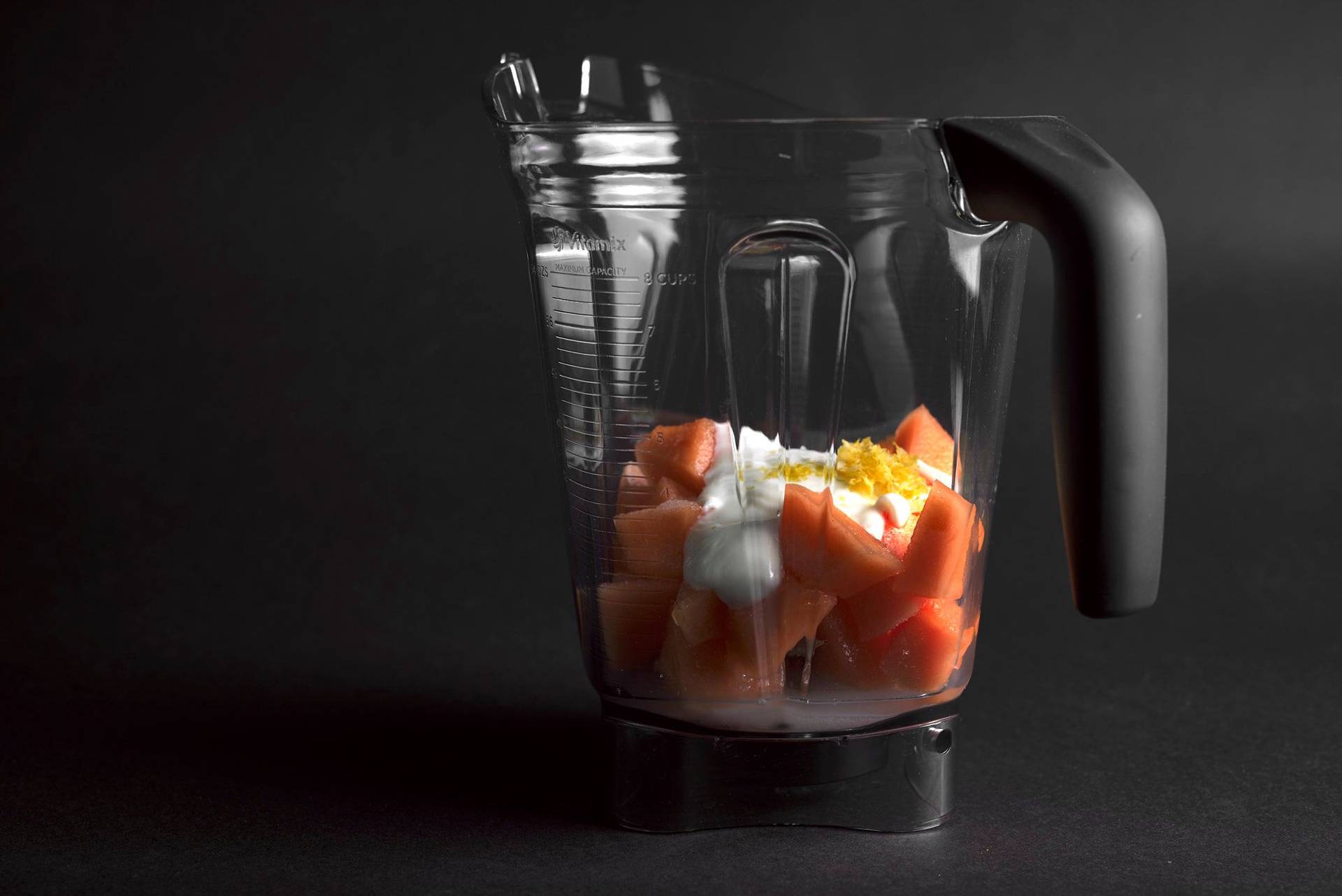 making-cantaloupe-melon-sorbet frozen cantaloupe melon with yoghurt in a mixing jug with black background