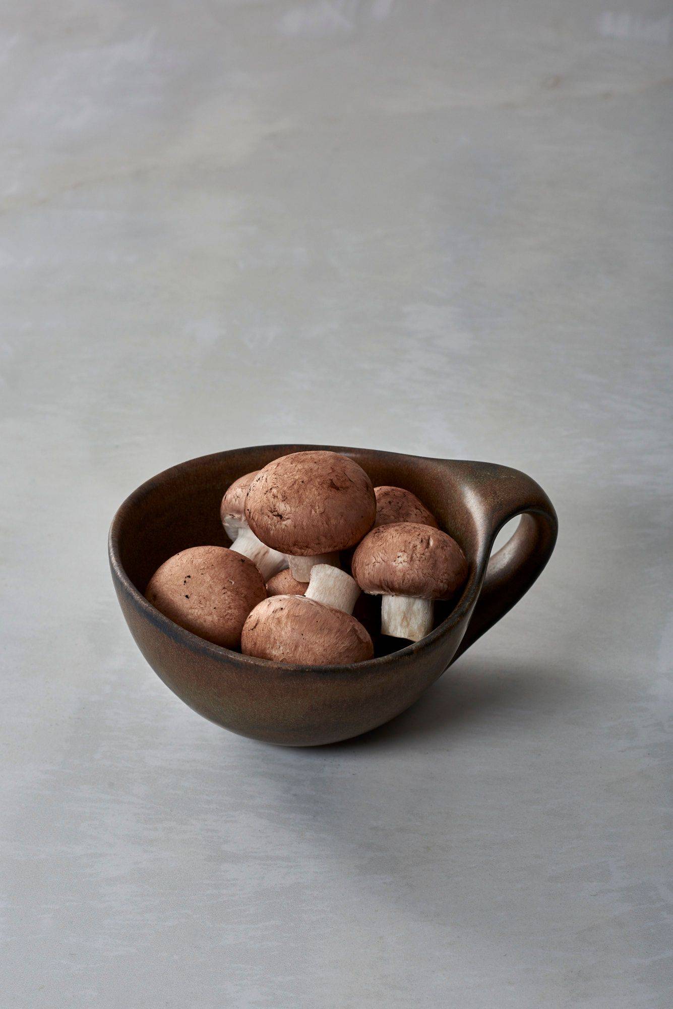 champignons in einer braunen keramiktasse mit weißem sapienstone top