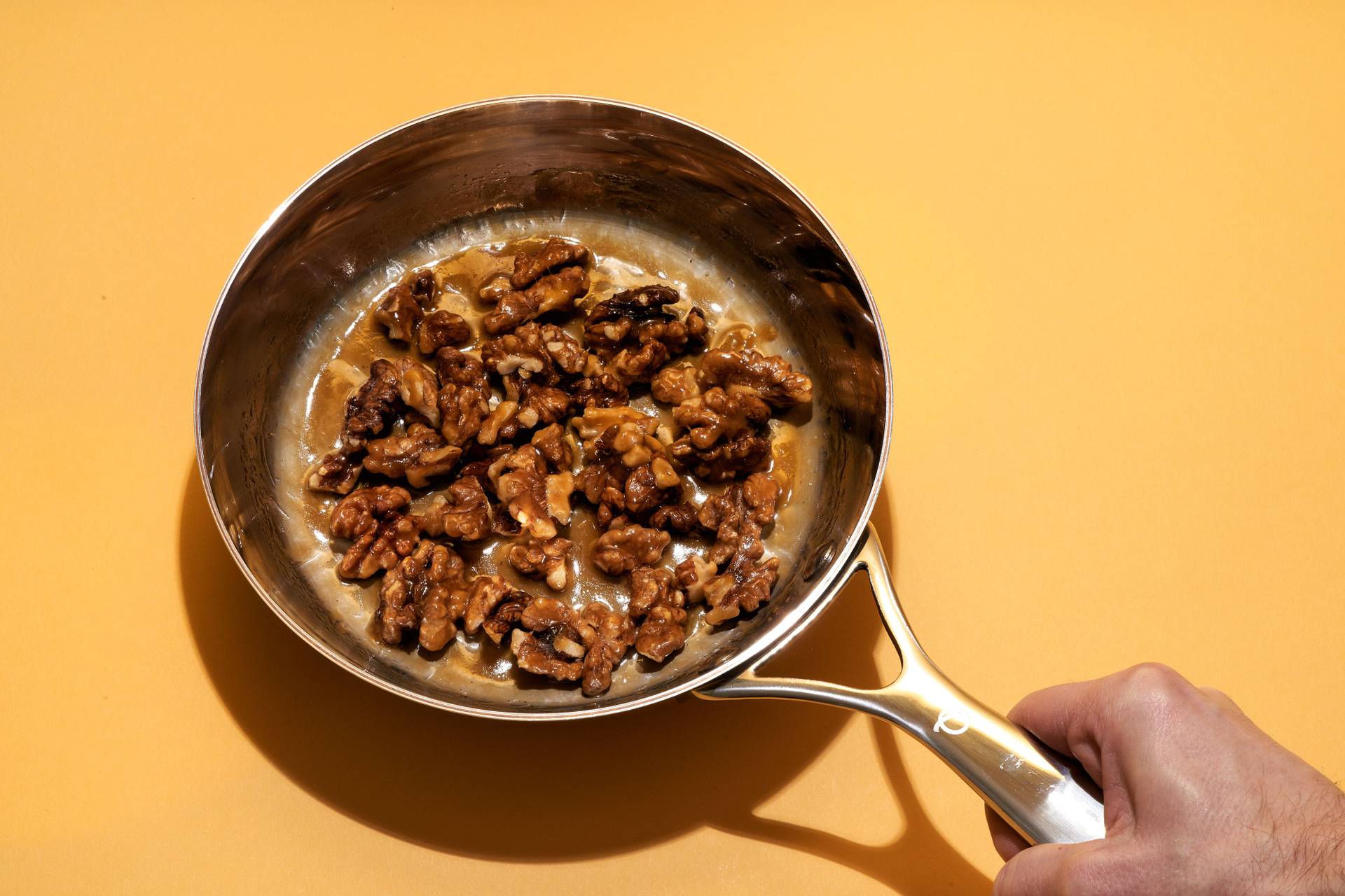 an olav pan with candied walnuts on yellow background