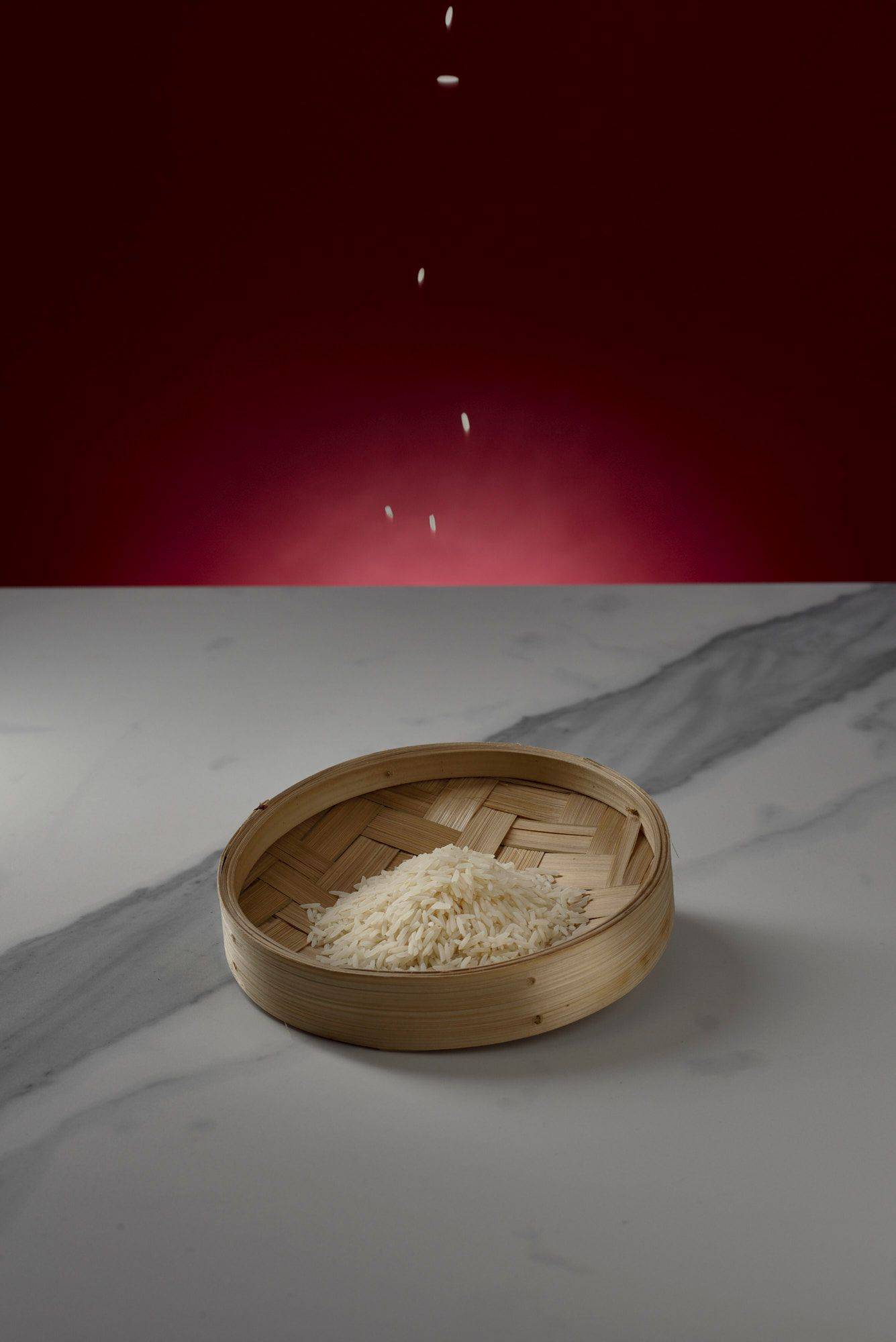 rice in a steam basket on marbled sapienstone top with red background