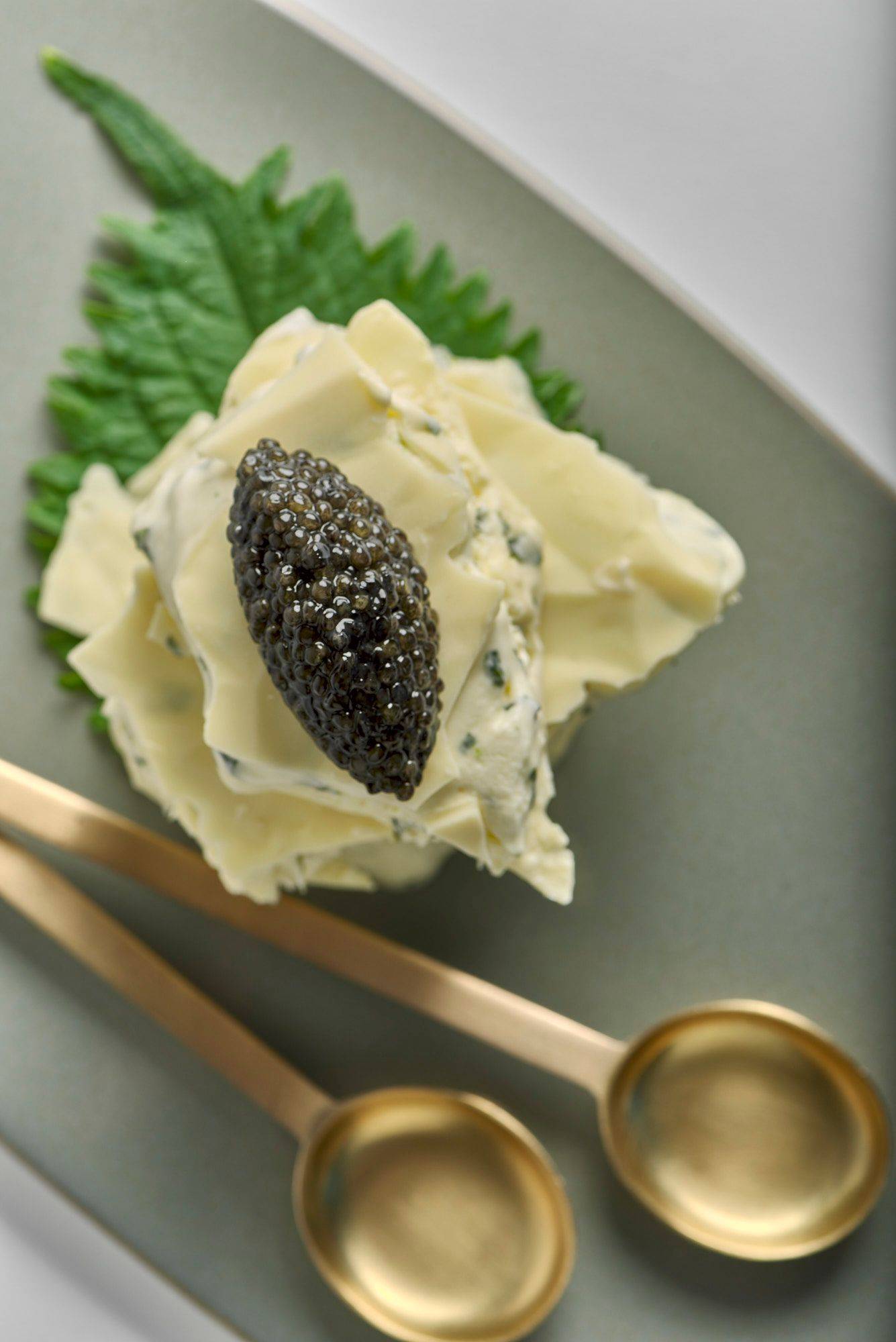 shiso and lime ice cream sandwich with caviar and white chocolate on a gray plate with white background