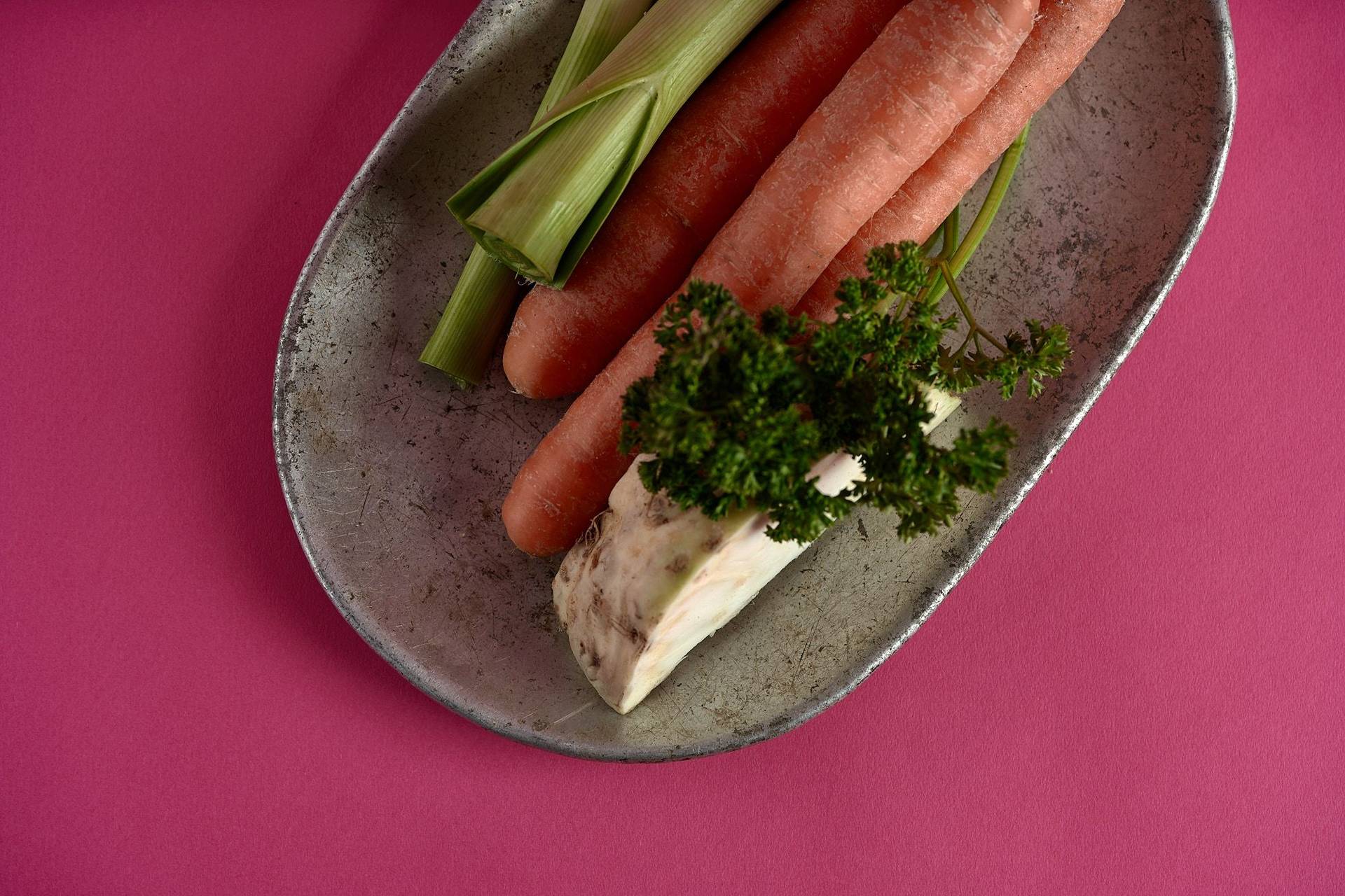 greens on a vintage aluminum plate on pink background