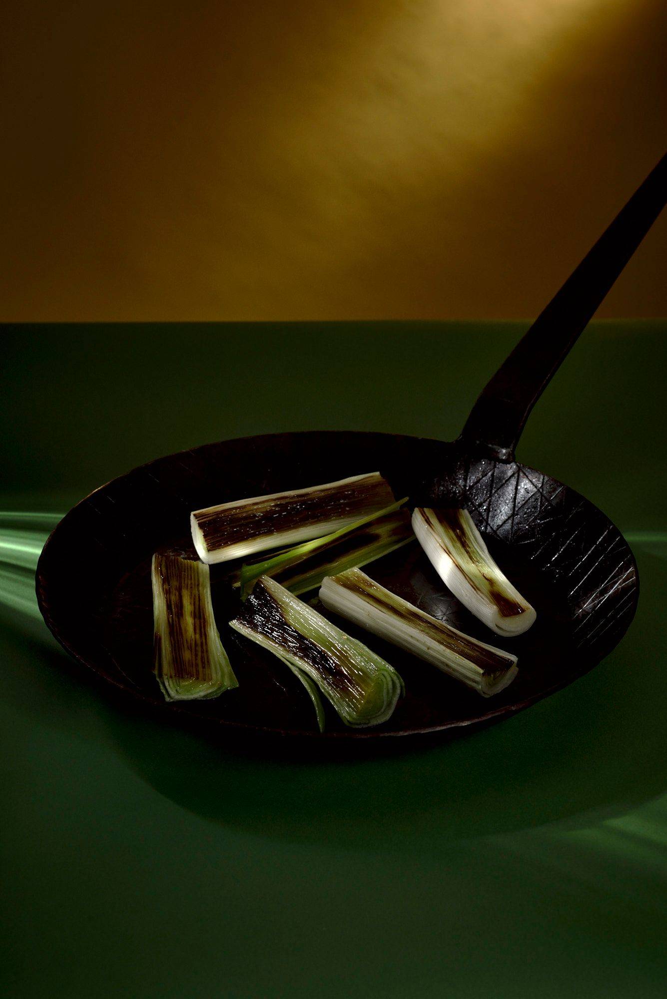 roasted leek in a pan with green yellow background