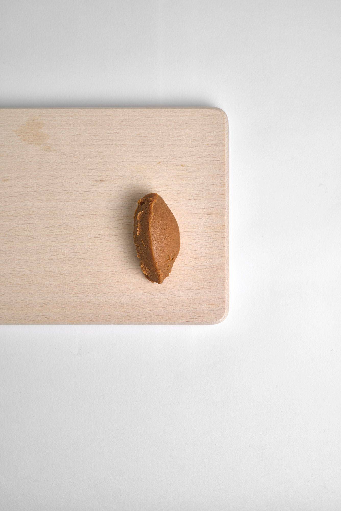 a spoon of miso paste on a wooden board on white background