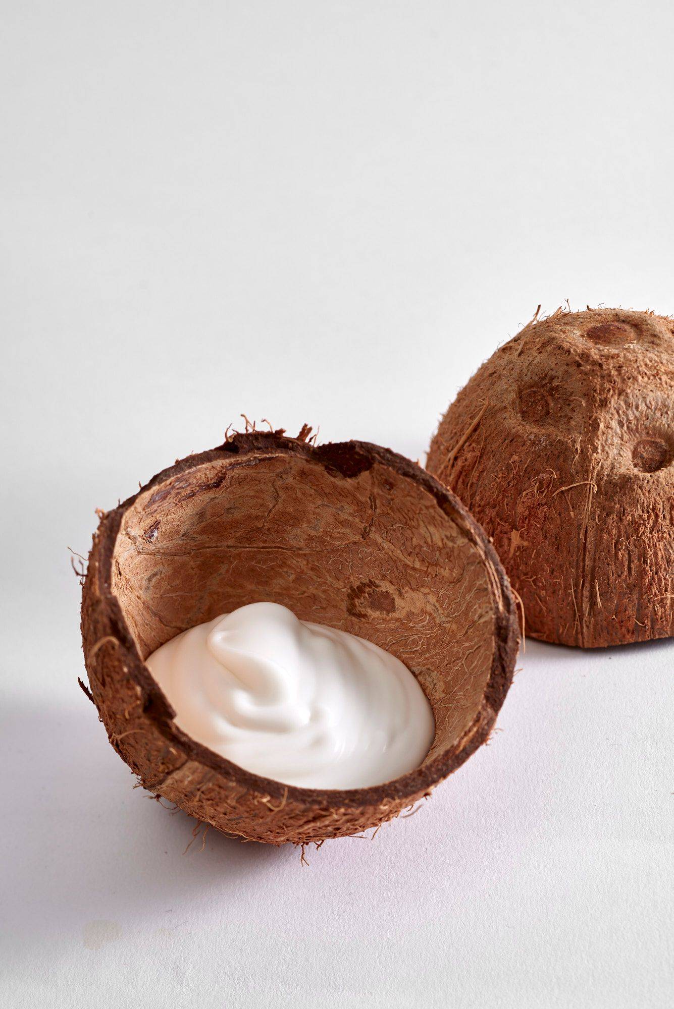 kokos creme in kokosnussschalen auf weißem hintergrund