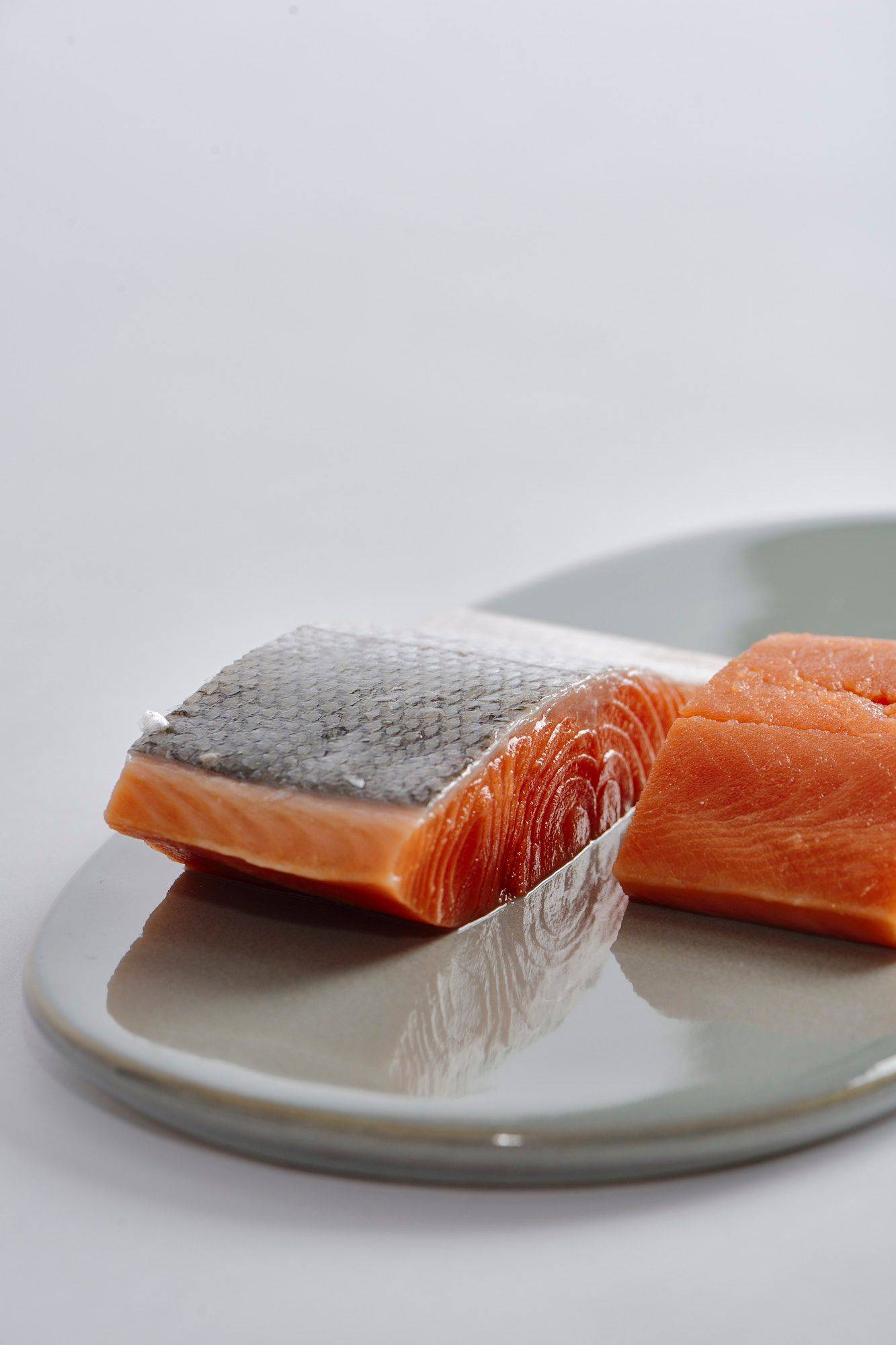 two pieces of salmon fillet on a gray plate with white background