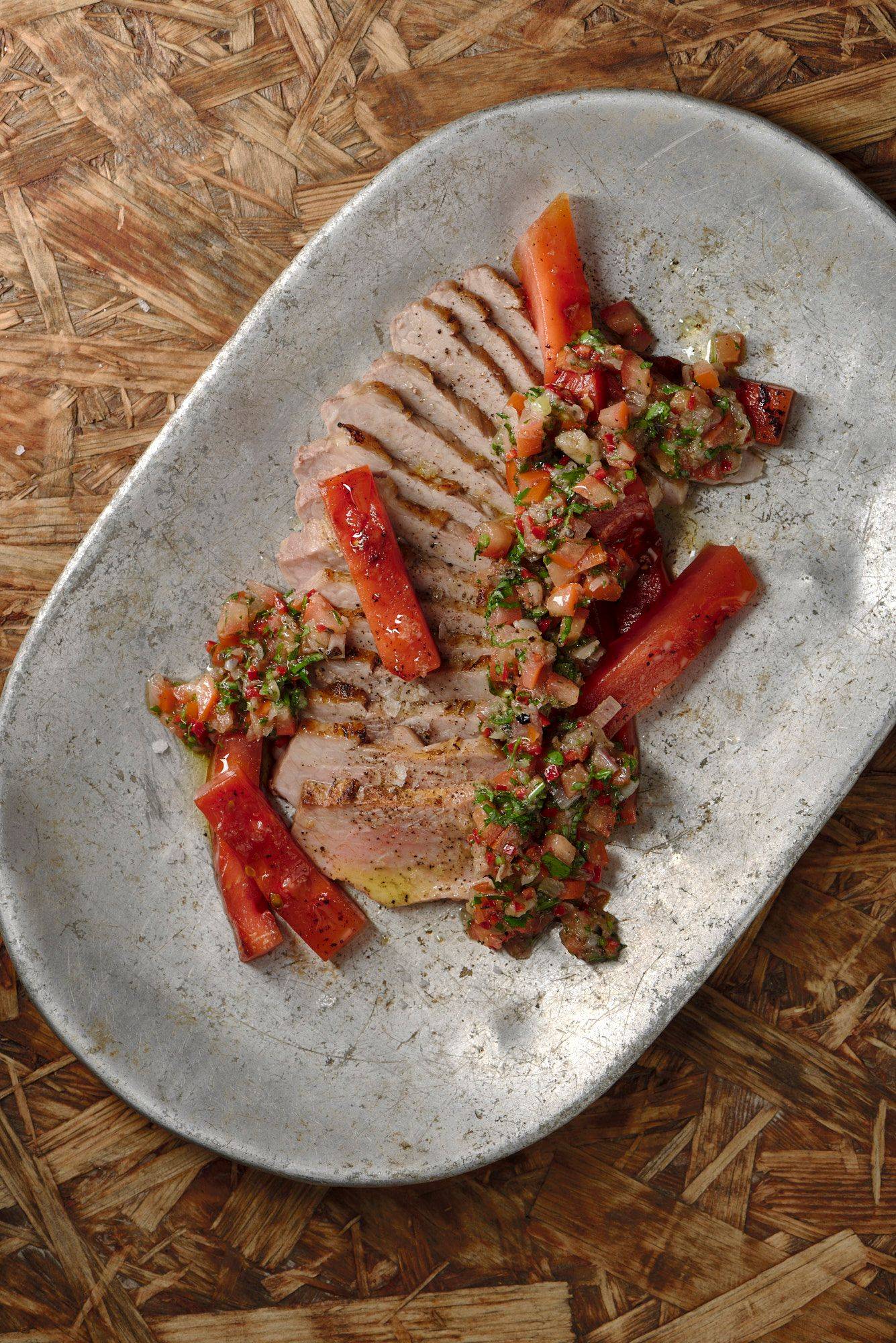 pork secreto with grilled watermelon and chimichurri on a vintage aluminum plate with wooden background