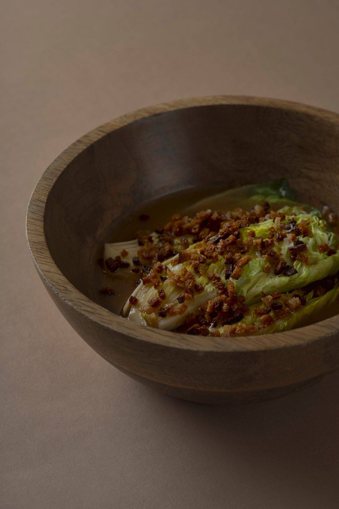 romaine lettuce with miso broth and sourdough in a wooden bowl with brown background