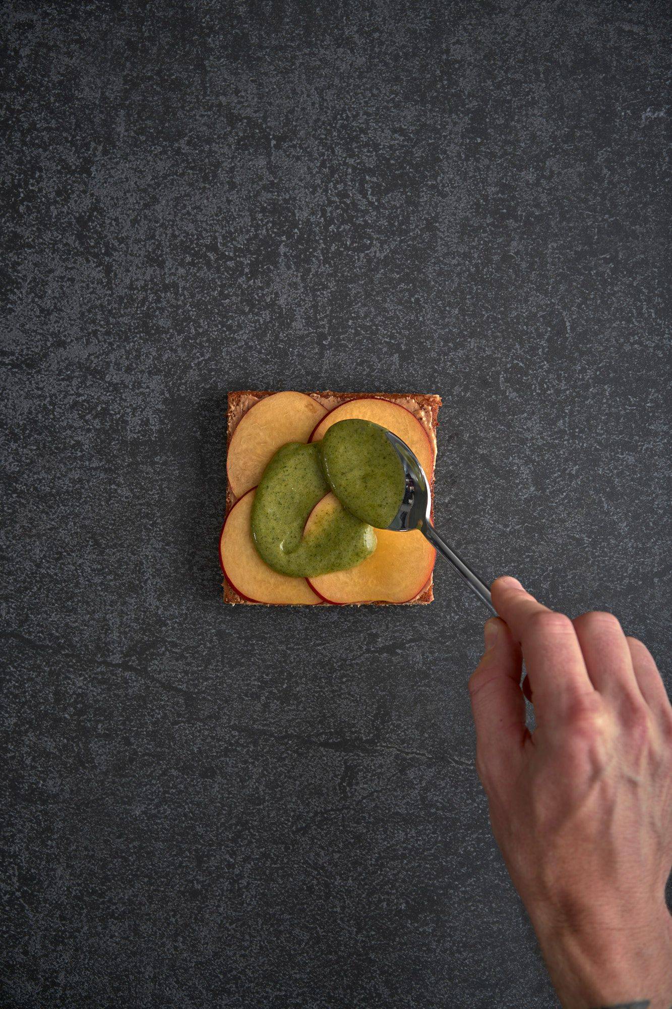 assembling a vegetarian asparagus katsu sando with nectarine and mint mayonnaise on a gray sapienstone top