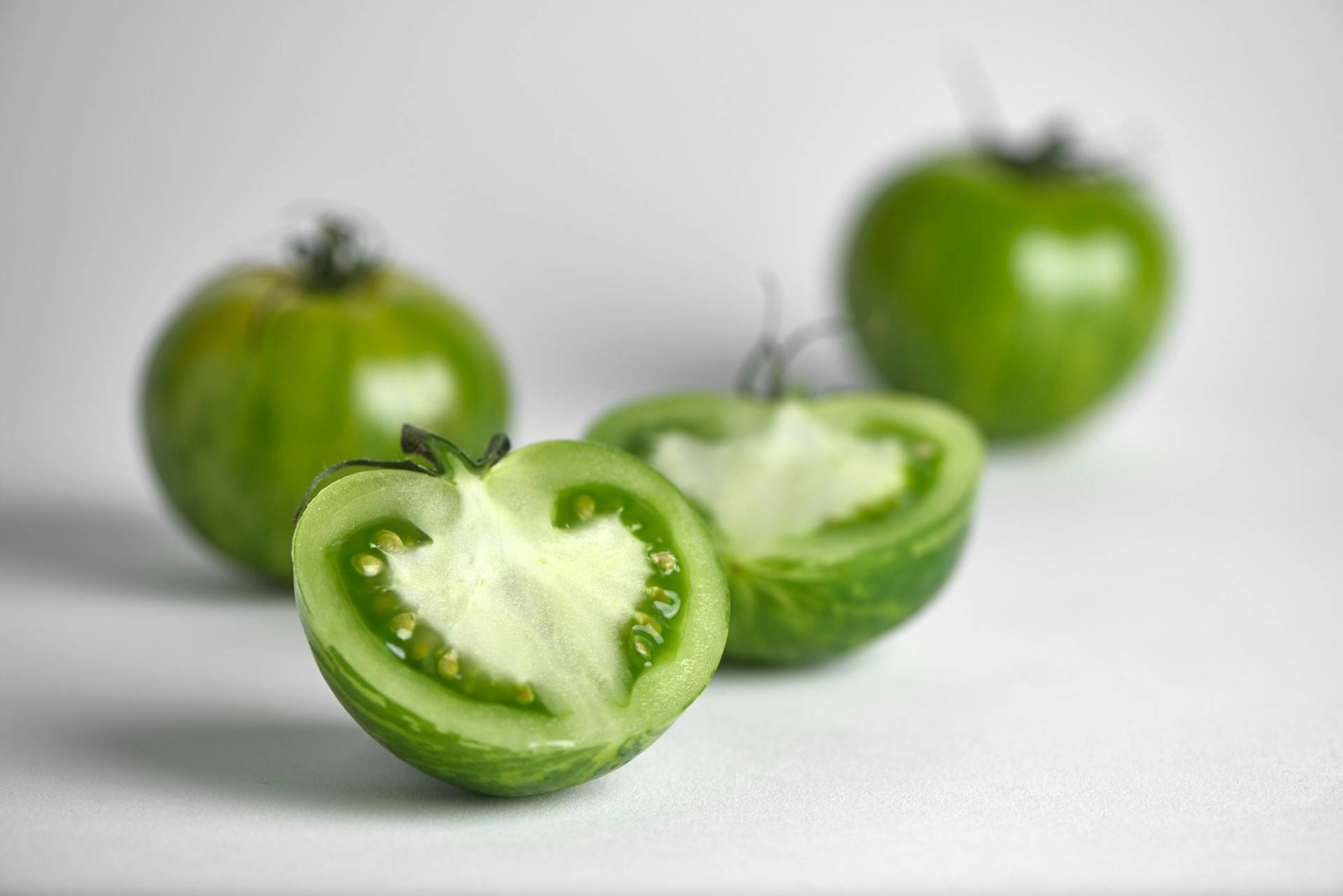 three green tomatoes with white background