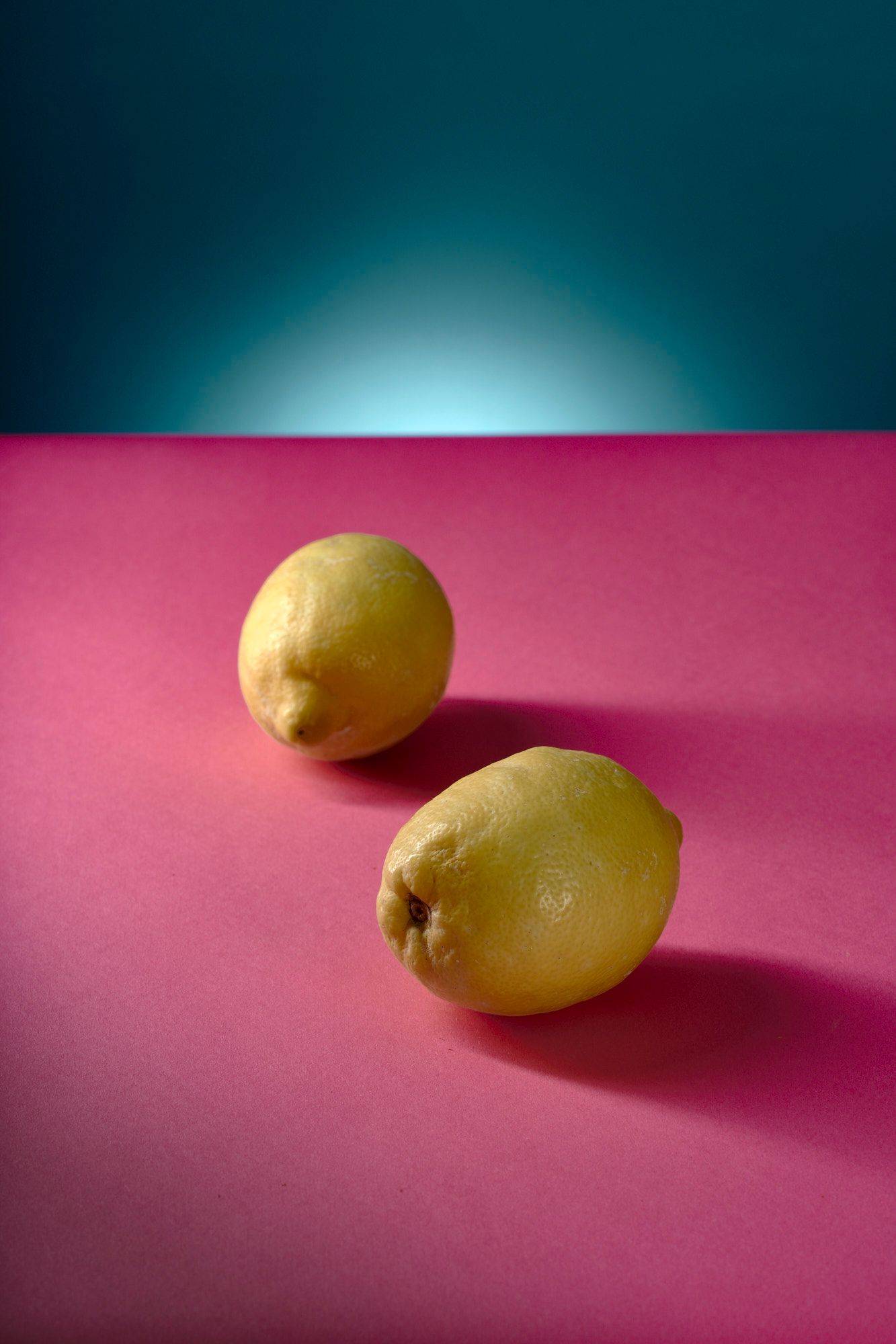 two lemons with pink and blue background