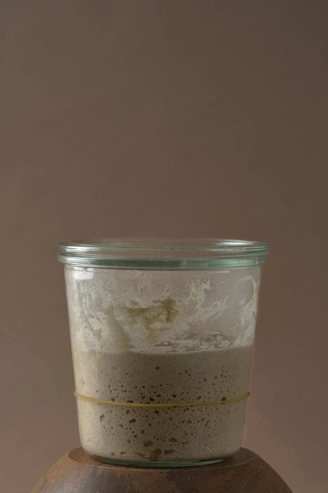 a jar of sourdough starter with brown background