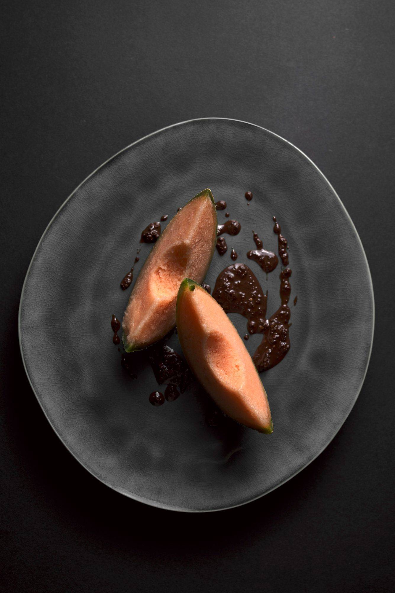 cantaloupe melon sorbet with spicy chocolate pesto on a gray plate with black background