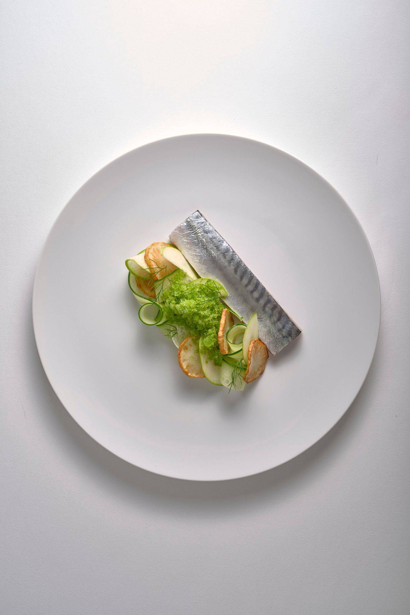 cured mackerel with jerusalem artichokes and dill granita on a white plate with white background