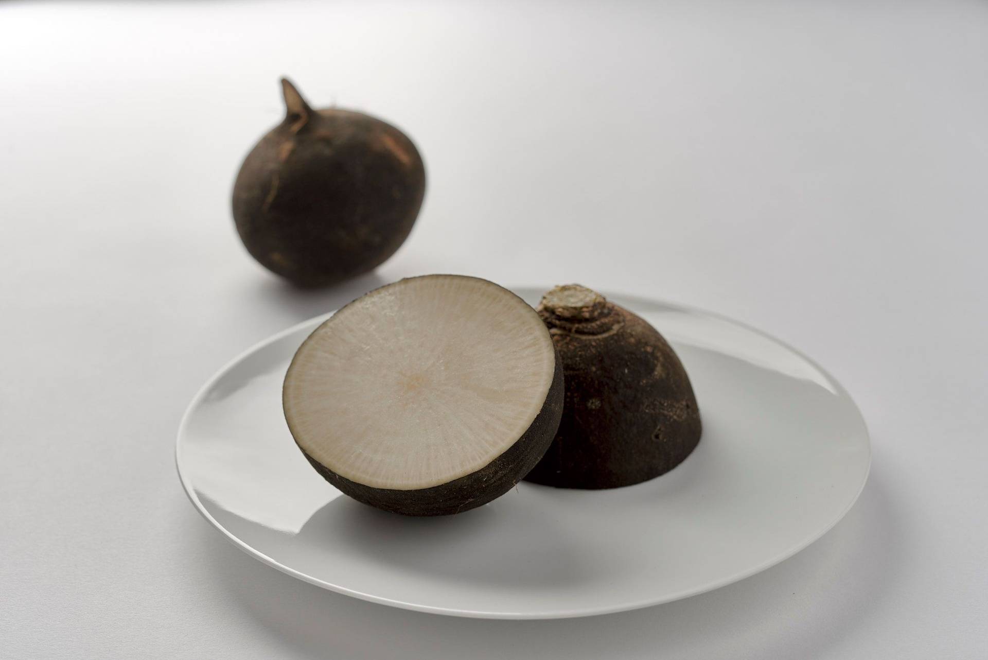 black-radish black radish on a white plate with white background