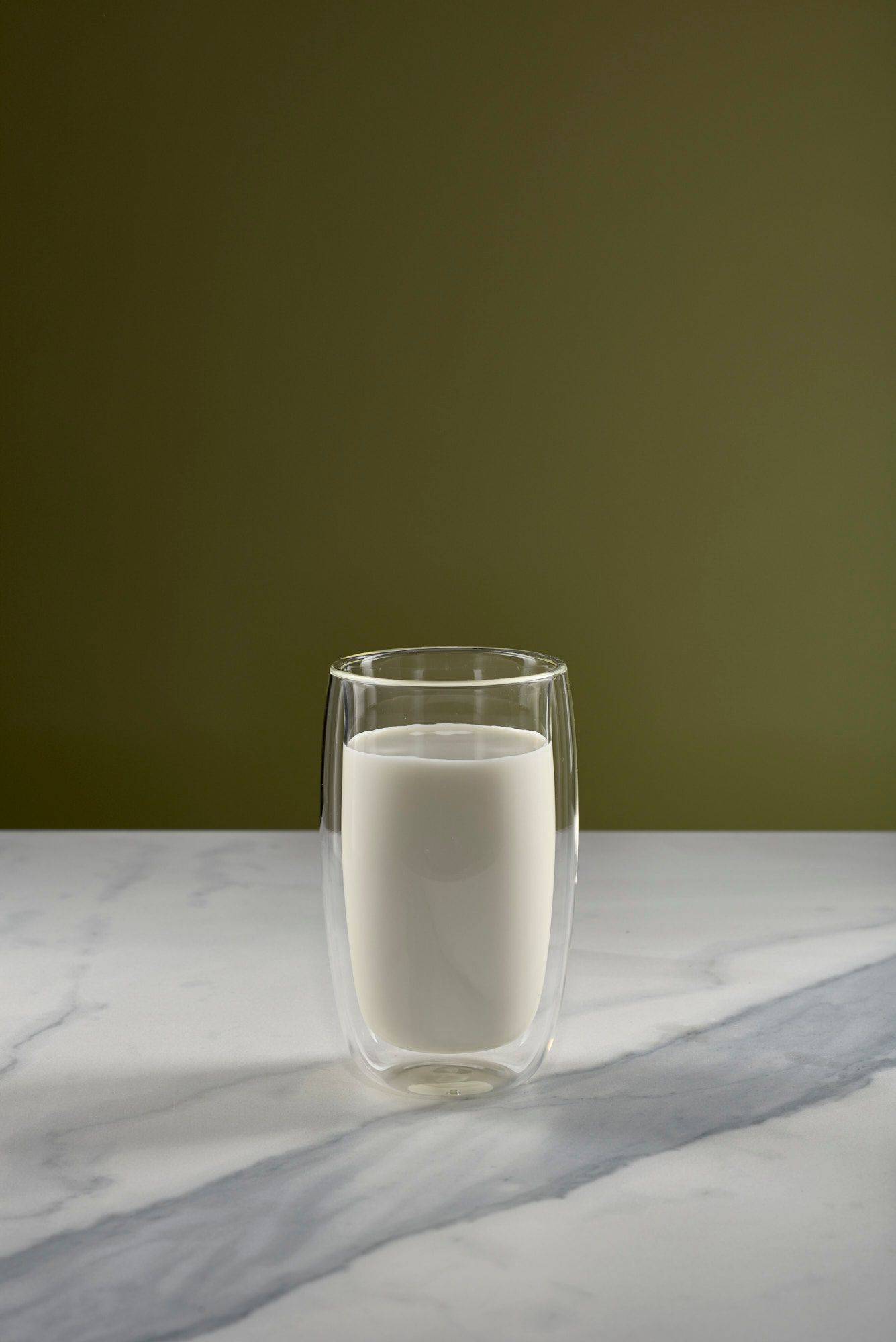 ein glas mit milch und sahne mit marmoriertem sapienstone top und grünem hintergrund