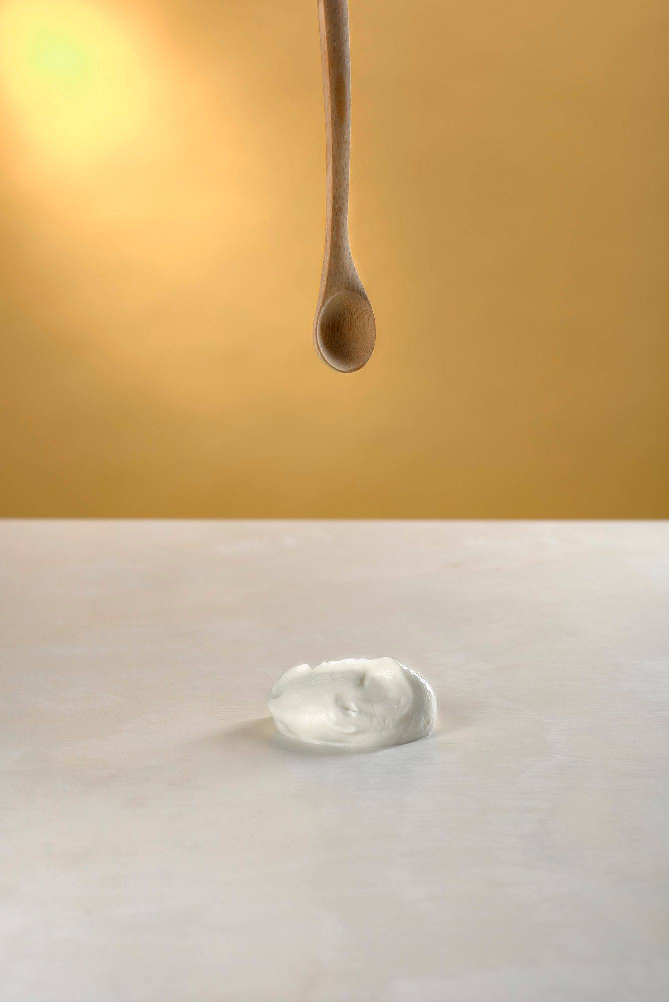 skyr with a wooden spoon on white sapienstone top with yellow background