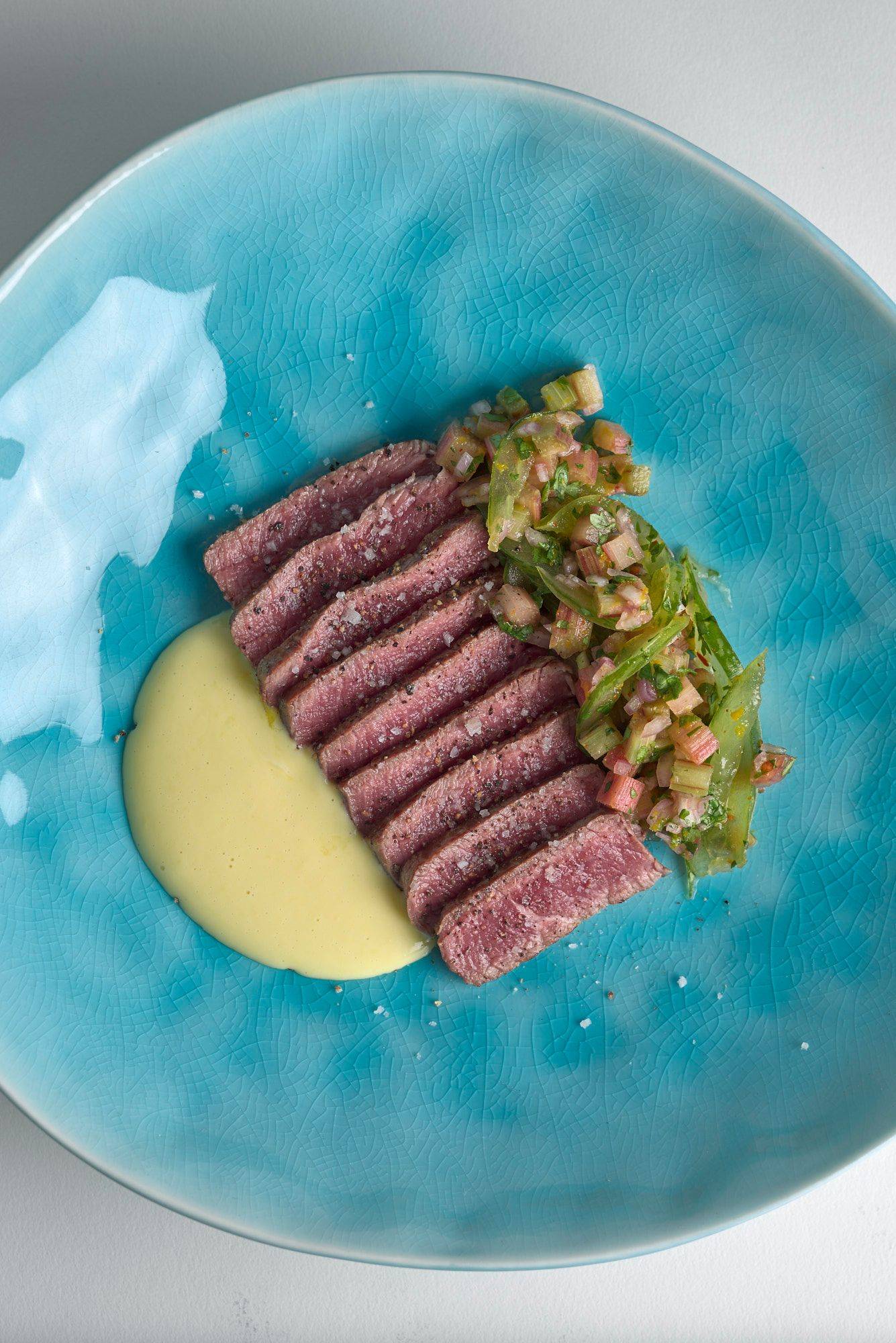 beef tataki with tomato salsa and ginger mayonnaise on a turquoise plate with white background
