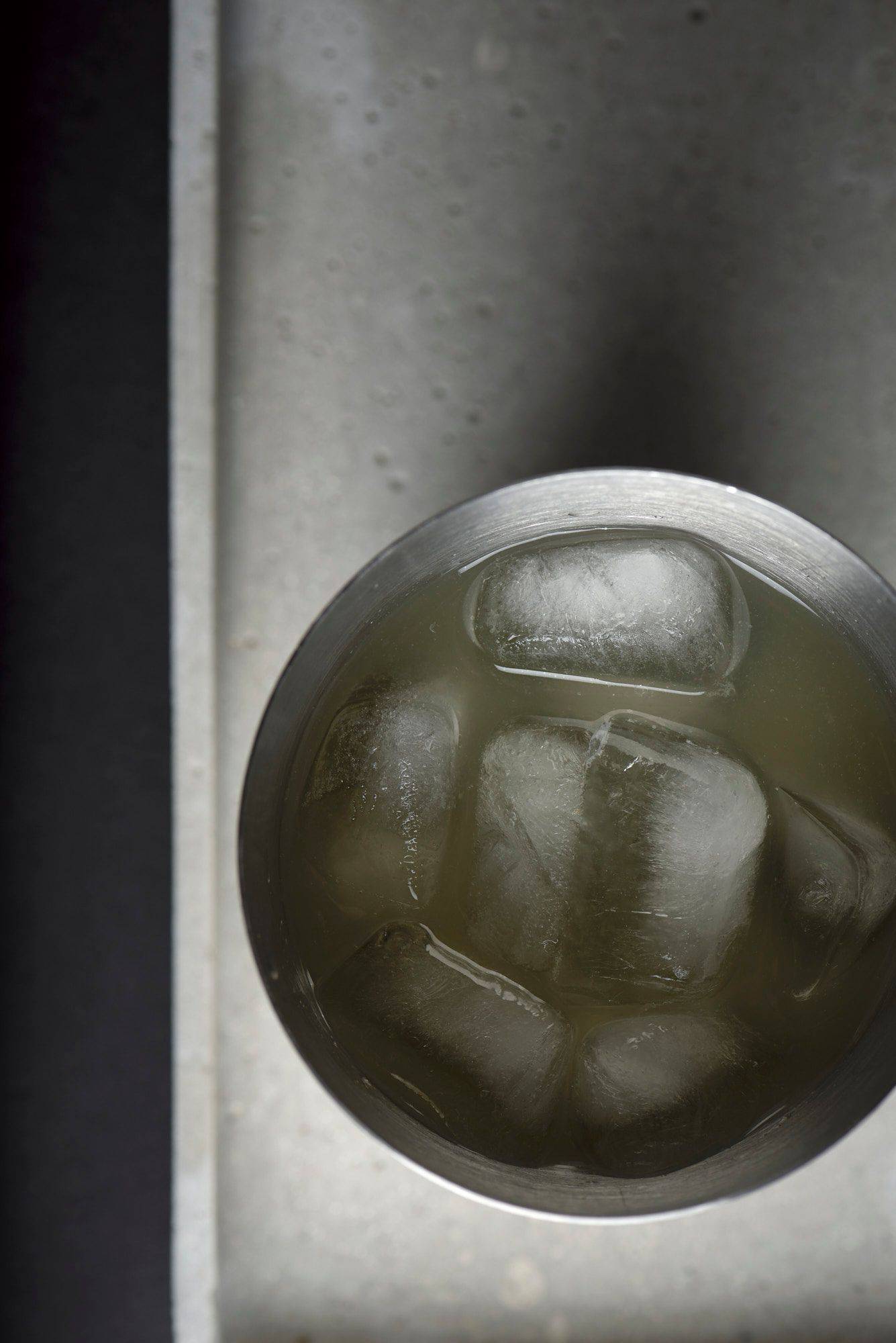 the-north shore cocktail in a jigger on a concrete plate on black background