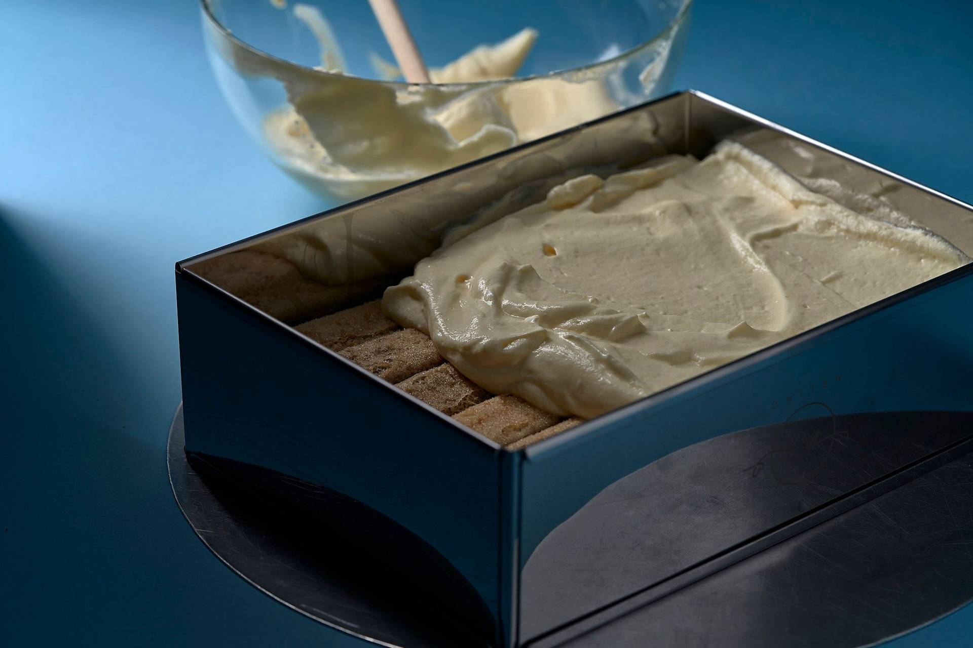 layering-an-original-italian-tiramisu-dessert layering an original italian tiramisu dessert with blue background