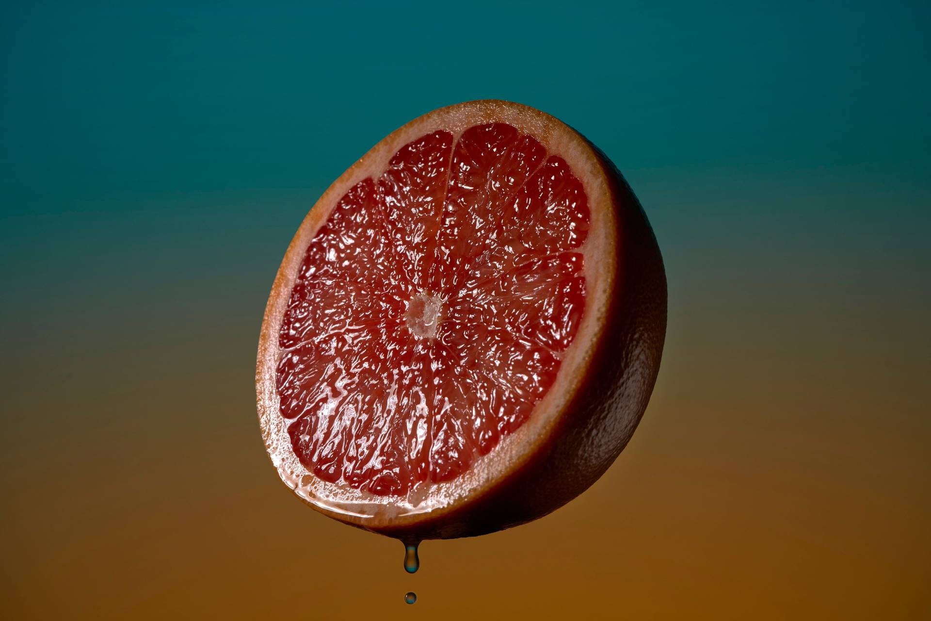 pink grapefruit vor blauem und orangenem hintergrund