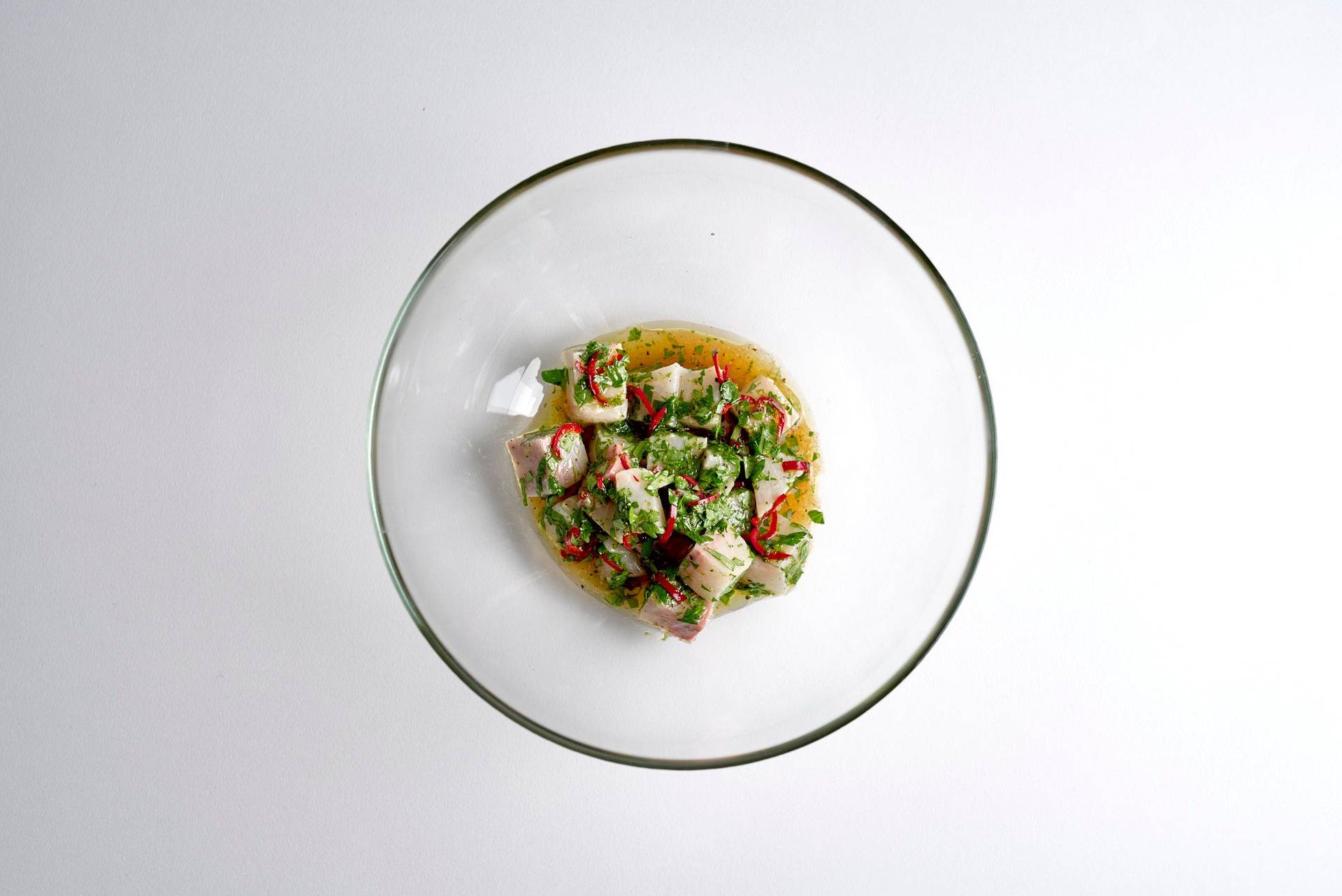 kingfish ceviche in a glass bowl on white background