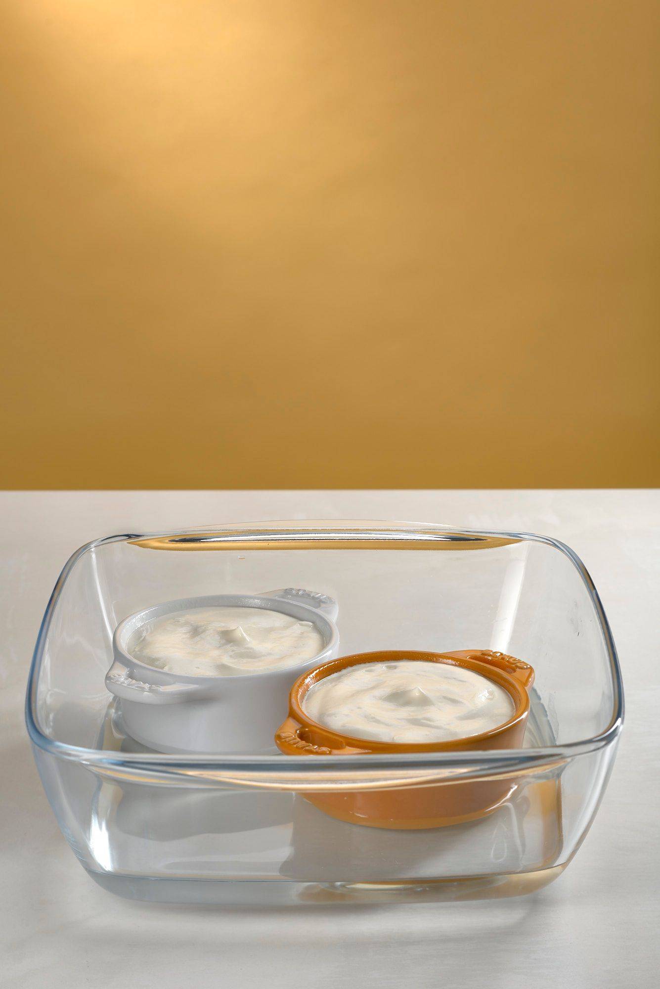 raw skyr souffle in staub cocottes on white sapienstone top with yellow background