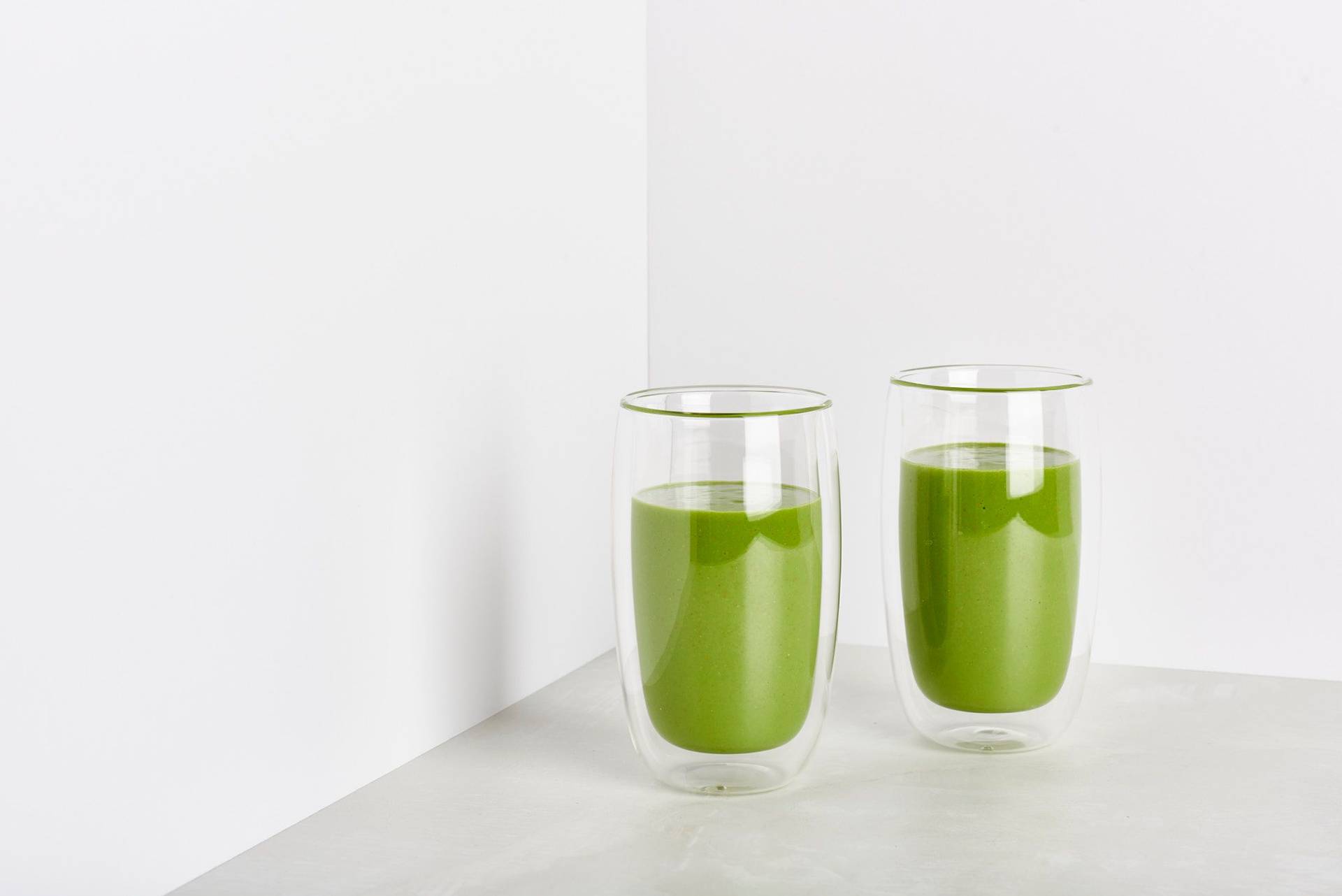 two glasses of sorrel and spelt smoothie on white background